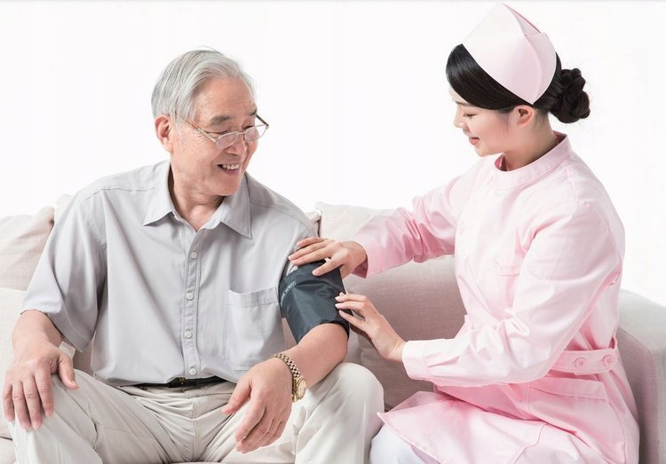 Starszy mężczyzna, któremu pielęgniarka mierzy ciśnienie na białym tle.