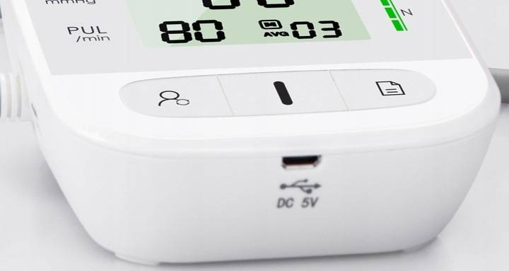 Zbliżenie białego ciśnieniomierza z wyświetlaczem i portem ładowania.