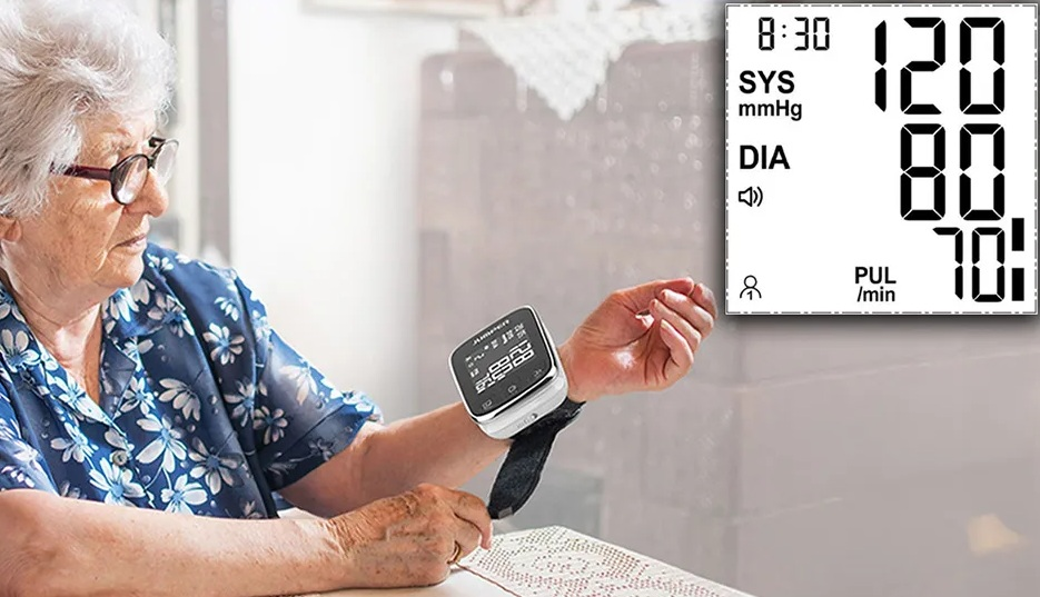 Starsza kobieta sprawdza ciśnienie krwi za pomocą monitora nadgarstka. Wyświetlacz pokazuje odczyty.