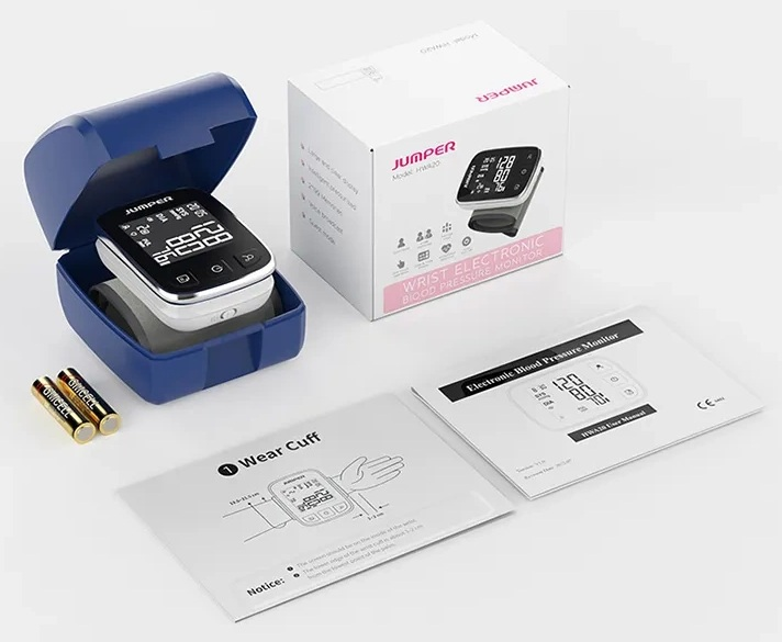 Ciśnieniomierz z akcesoriami. Widoczny monitor, pudełko, instrukcja i baterie.