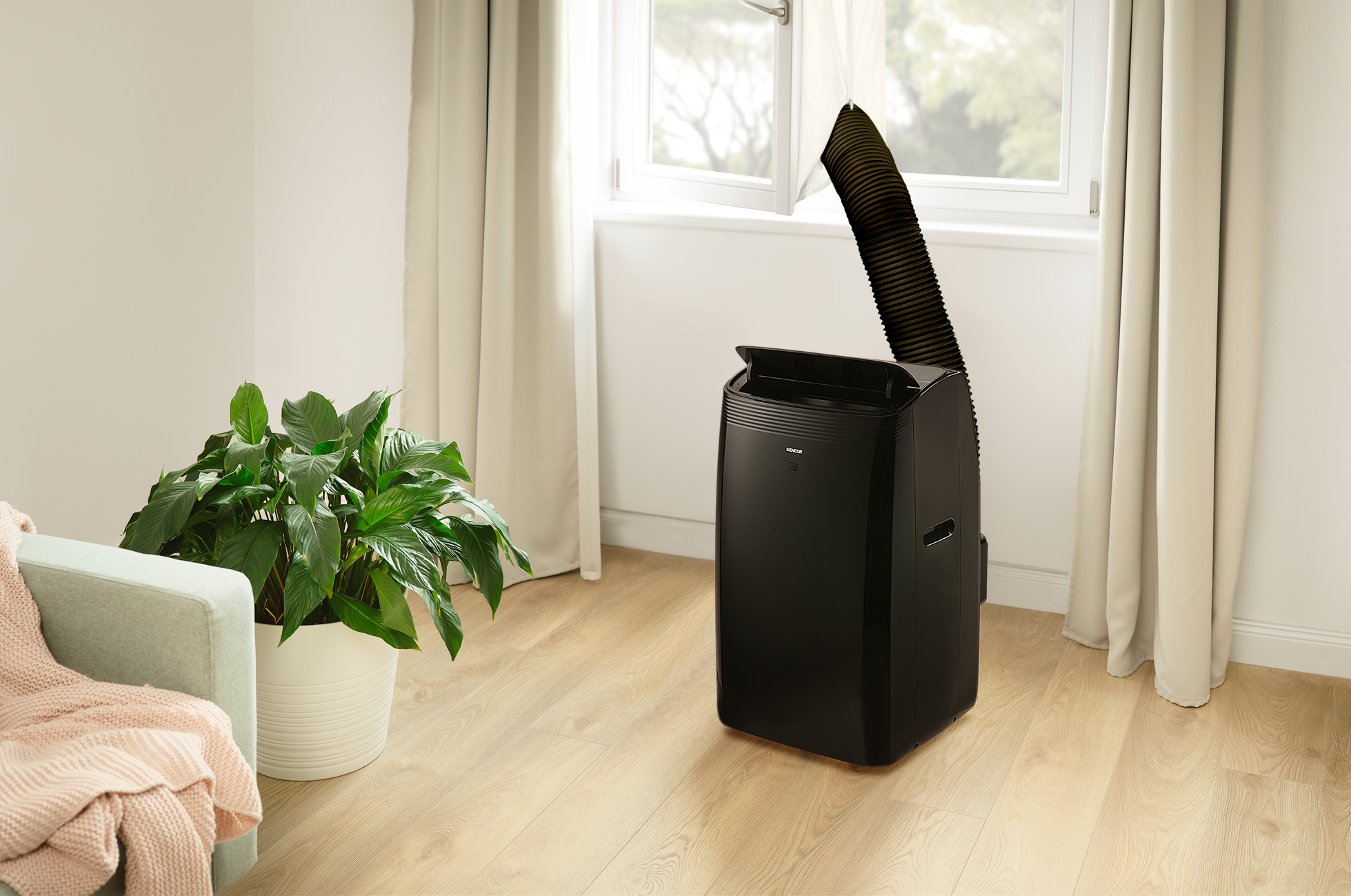 Czarny przenośny klimatyzator w pobliżu okna z przewodem wylotowym na zewnątrz.