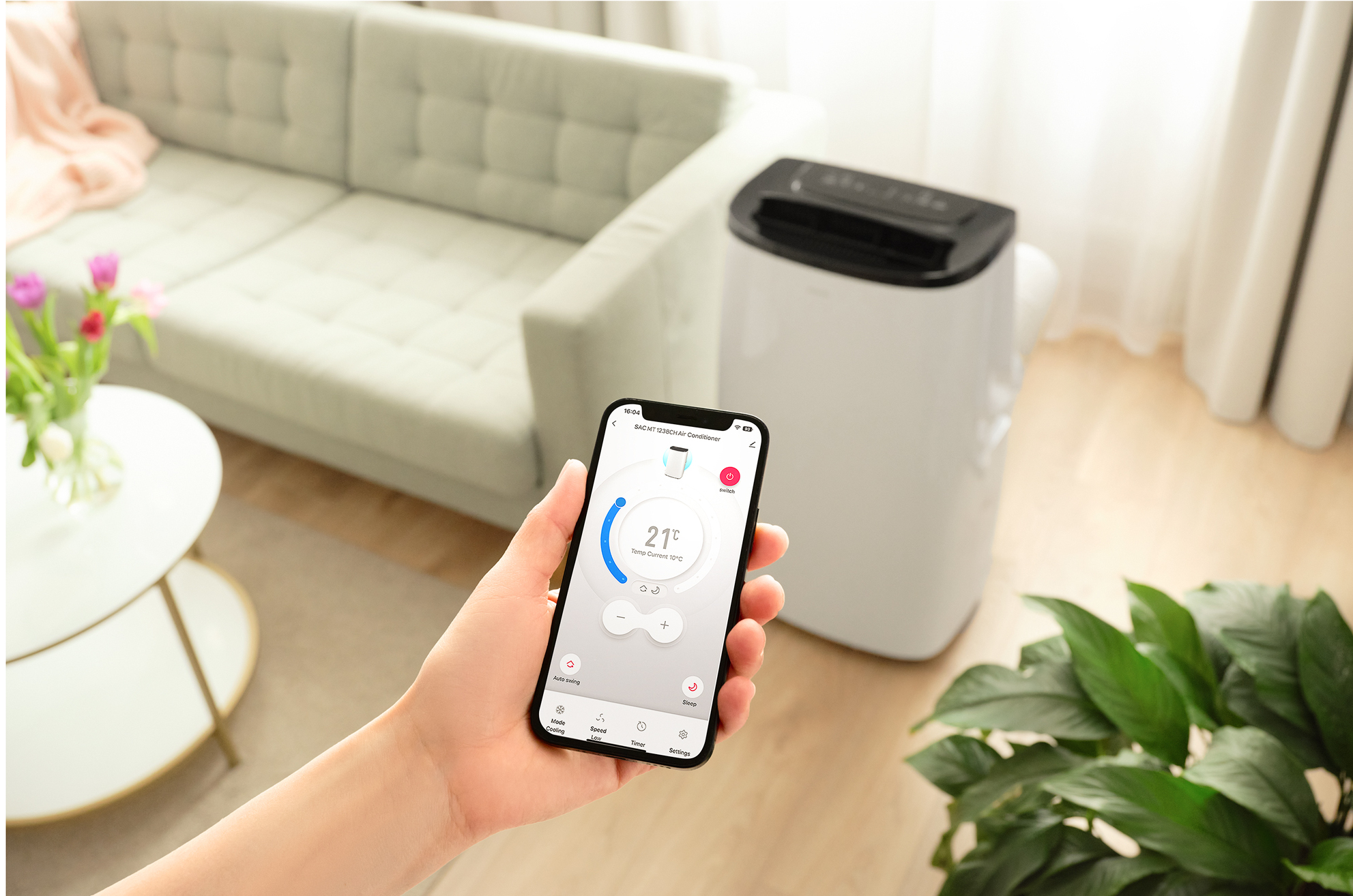 Dłoń trzymająca telefon sterujący klimatyzacją w salonie.