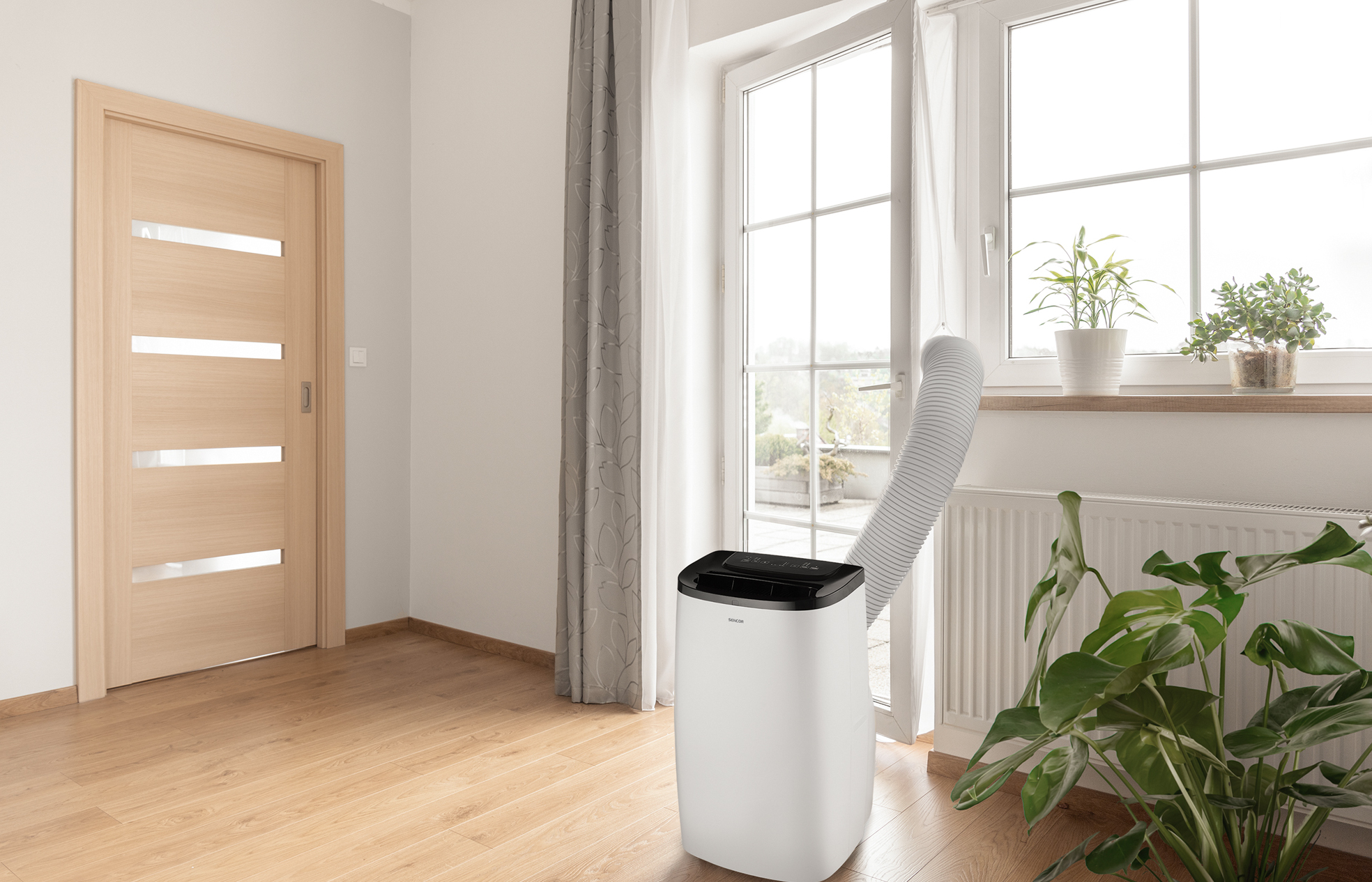 Biała przenośna klimatyzacja z wężem podłączonym do okna.