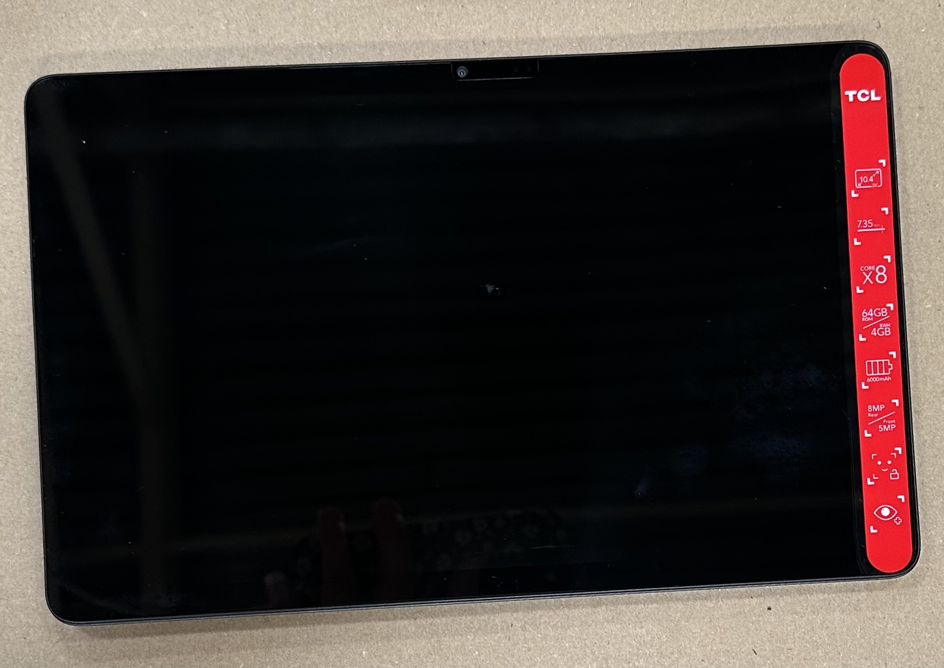 Czarny tablet TCL z aparatem. Ma czarny ekran i czerwoną ramkę ze specyfikacją z boku.