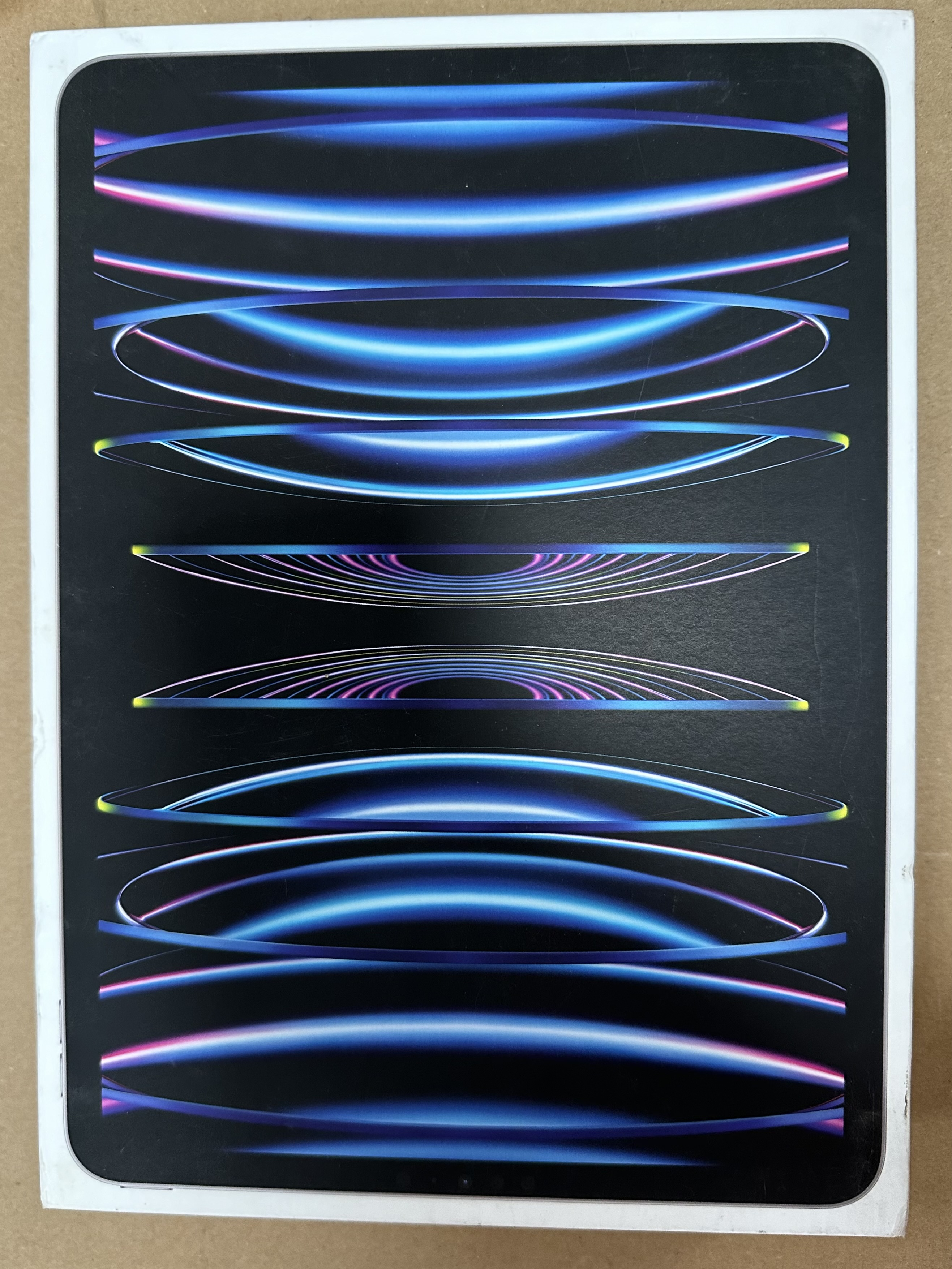 Pudełko iPada w czarnym kolorze z kolorowymi zakrzywionymi liniami.