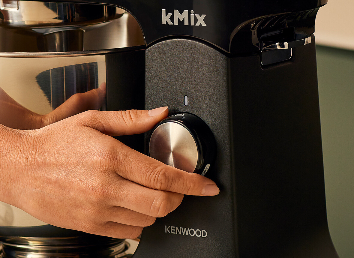 Zbliżenie dłoni obracającej pokrętło prędkości w czarnym mikserze Kenwood kMix.