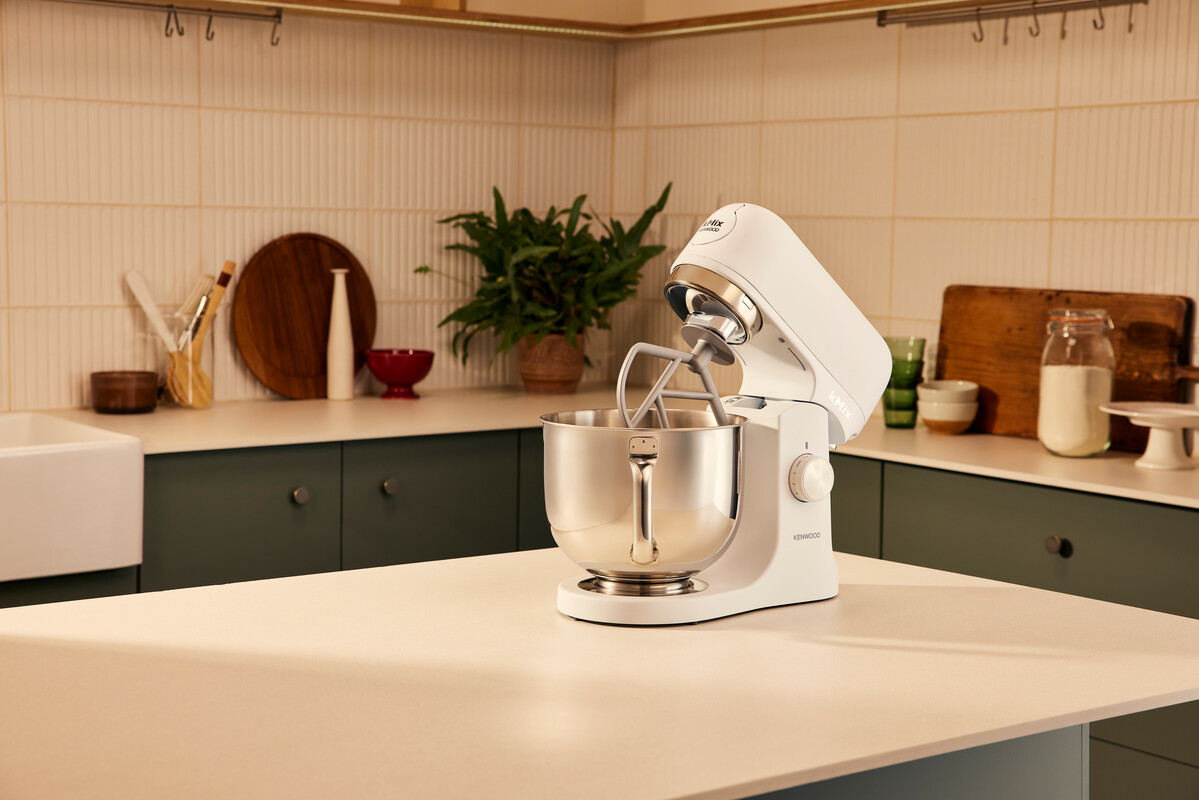 Biały mikser KitchenAid stoi na białym blacie w nowoczesnej kuchni.