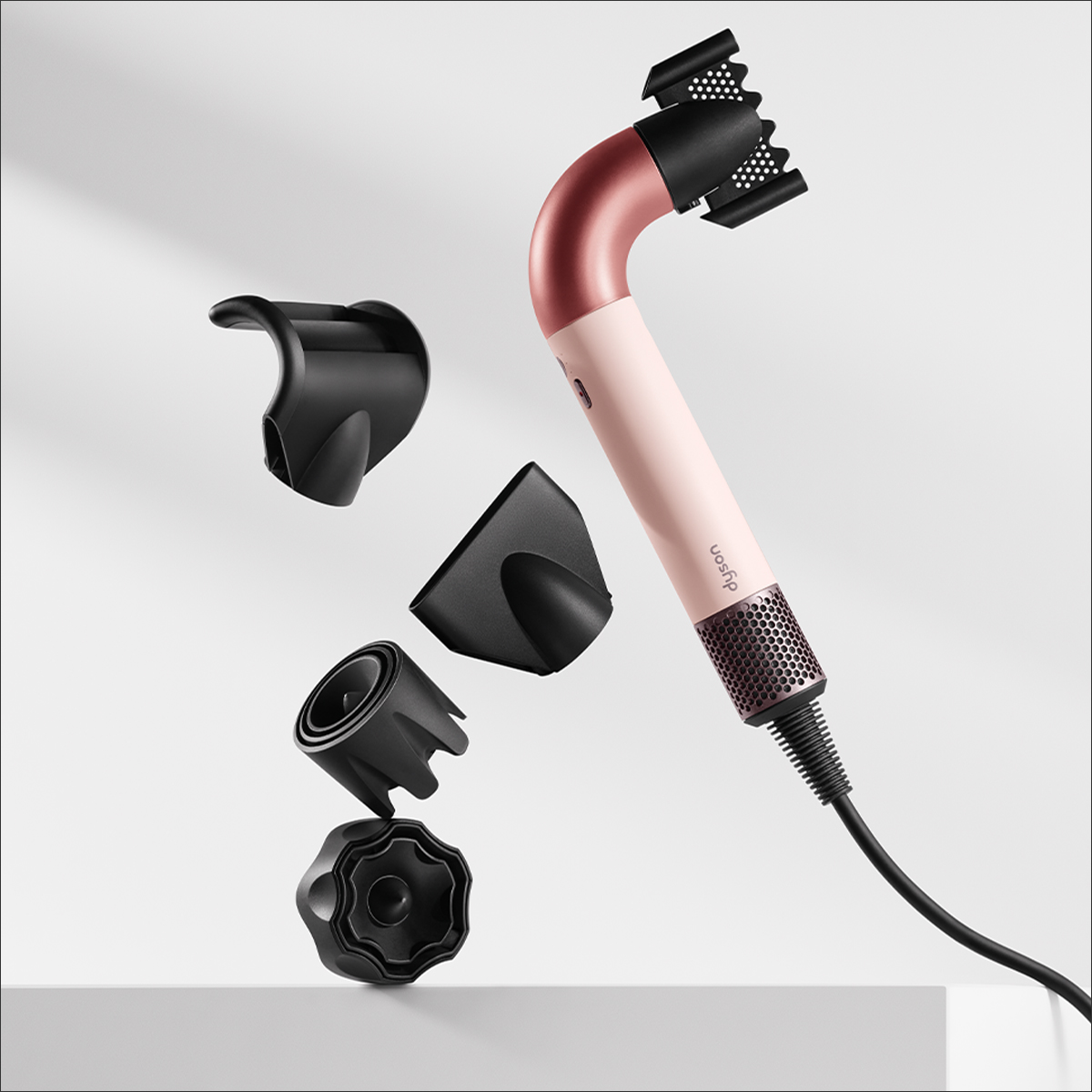 Secador de pelo Dyson con accesorios, cuerpo rosa, accesorios negros, flotando en blanco.