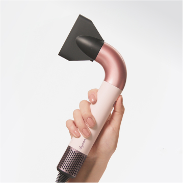 Mano sosteniendo secador de pelo Dyson rosa y negro. Fondo blanco, primer plano.