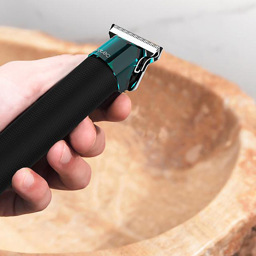 Dłoń trzymająca czarno-turkusową trymer. Obok kamiennej miski.