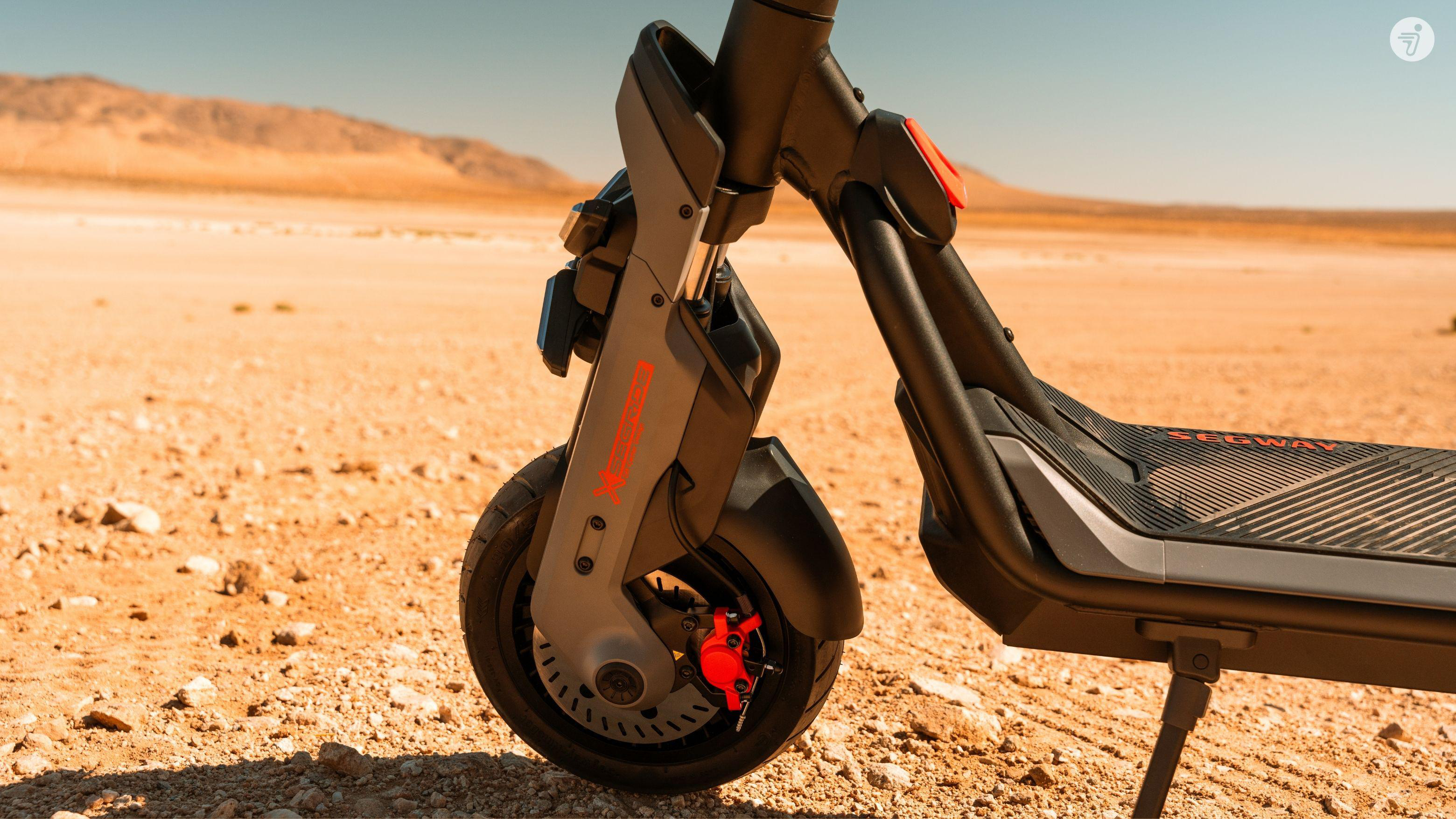 E-Scooter-Vorderrad mit roter Bremse in Wüstenlandschaft.