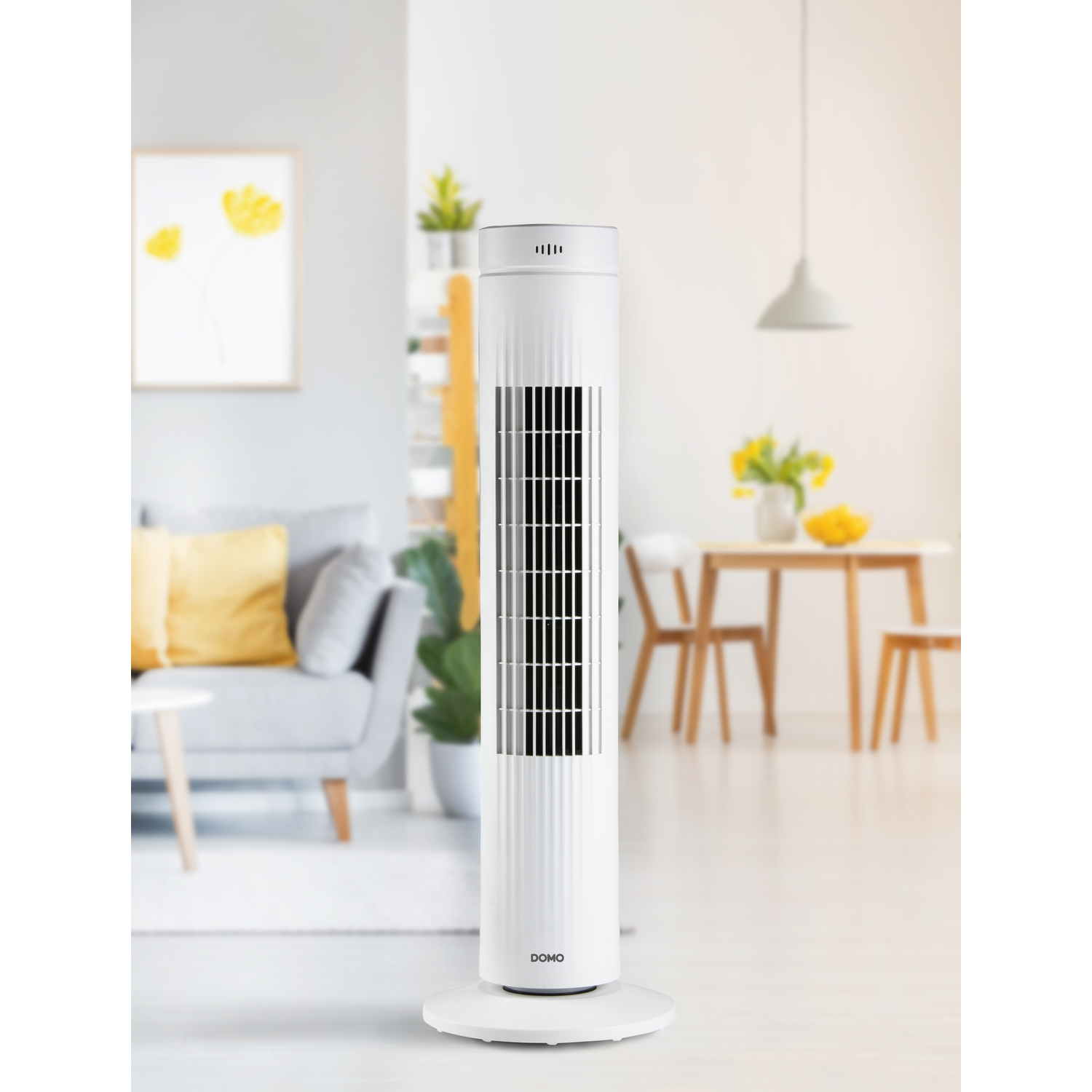 Witte torenventilator in een woonkamer met een bank en tafel.