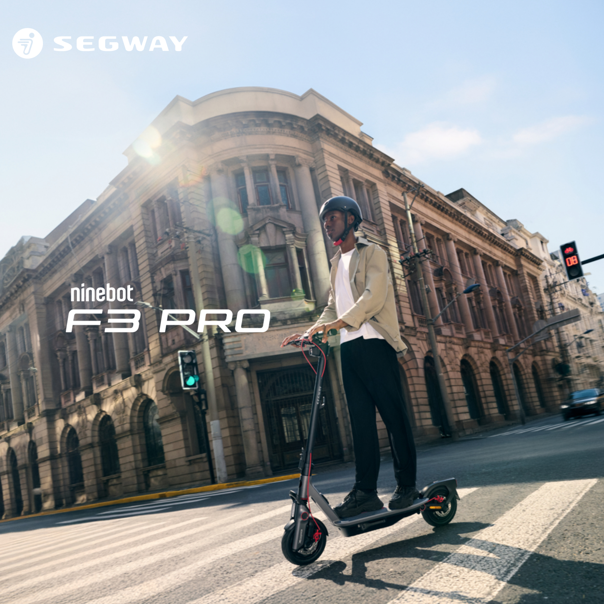 Eine Person fährt mit einem Segway Ninebot F3 Pro auf einer Straße, Gebäude im Hintergrund.