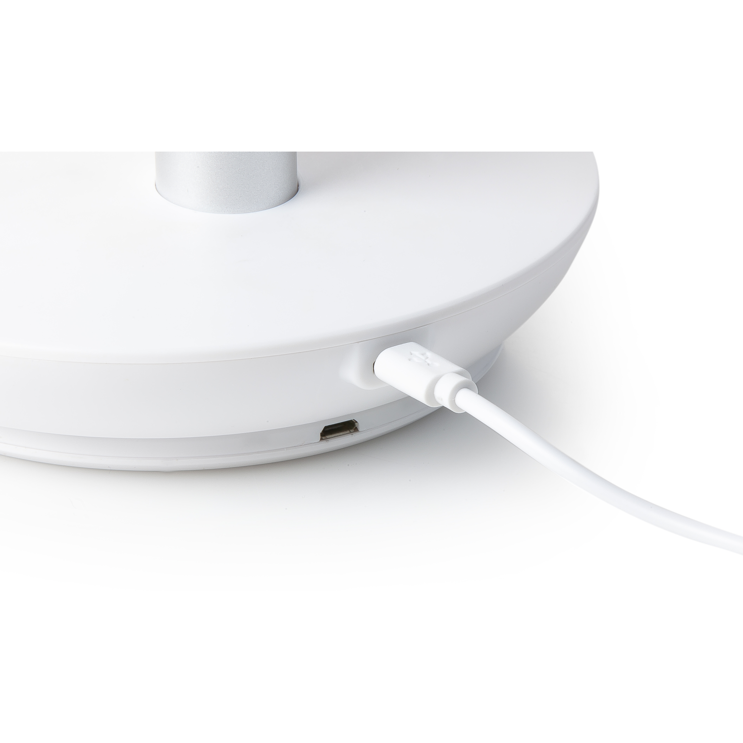 A close-up of the base of a white lamp with a charging port and white cable.