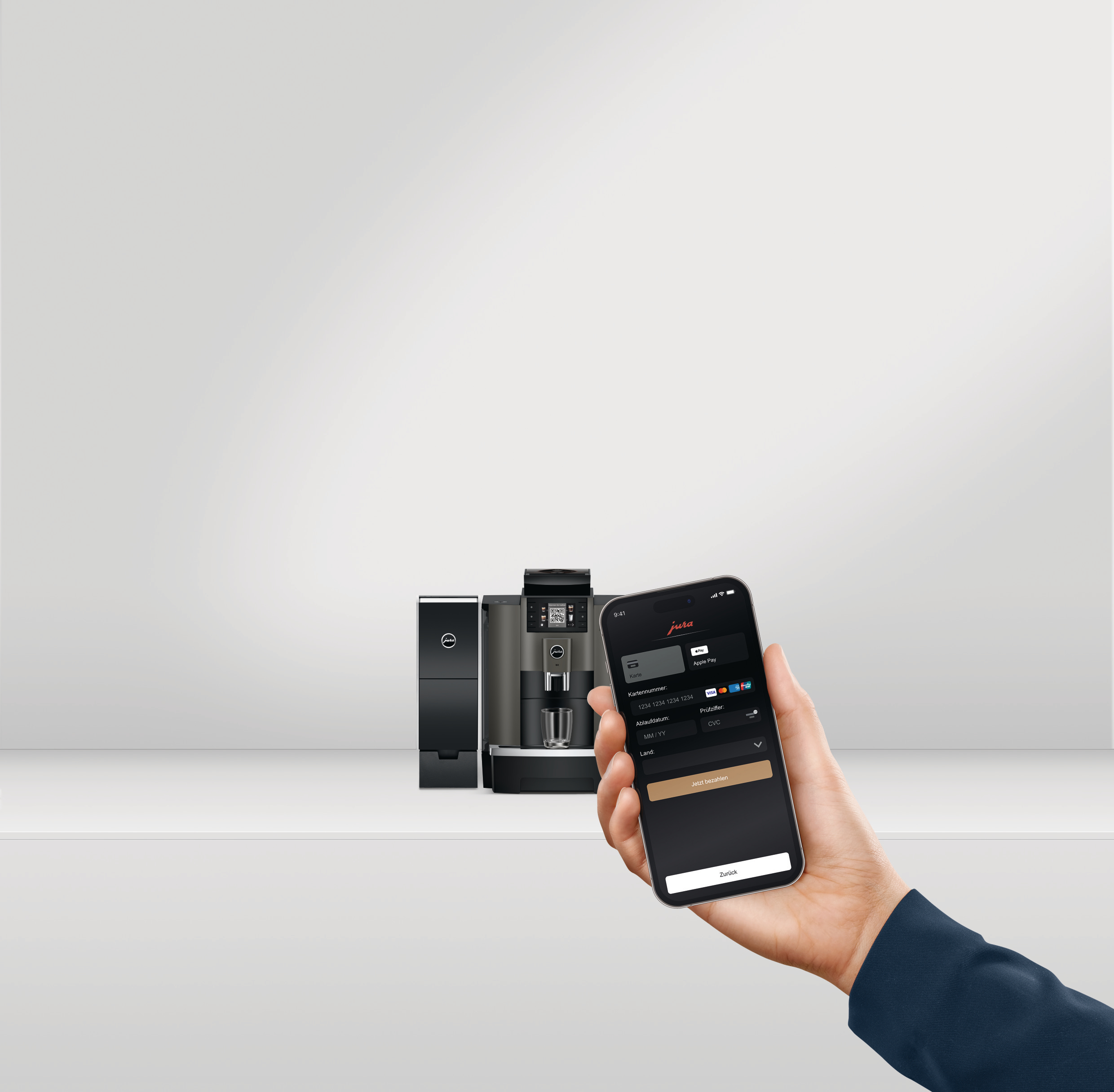 Hand hält Telefon über Espressomaschine. Das Telefon zeigt Zahlungsoptionen.
