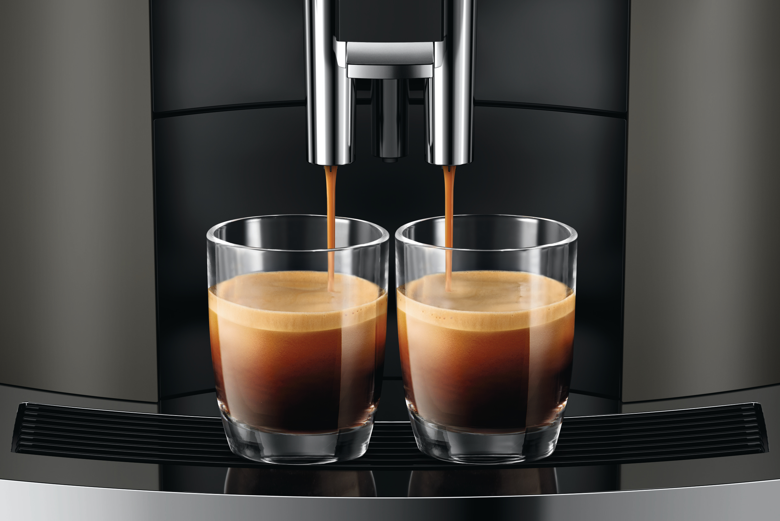 Espressomaschine, die zwei Tassen Kaffee in klaren Gläsern ausgibt.