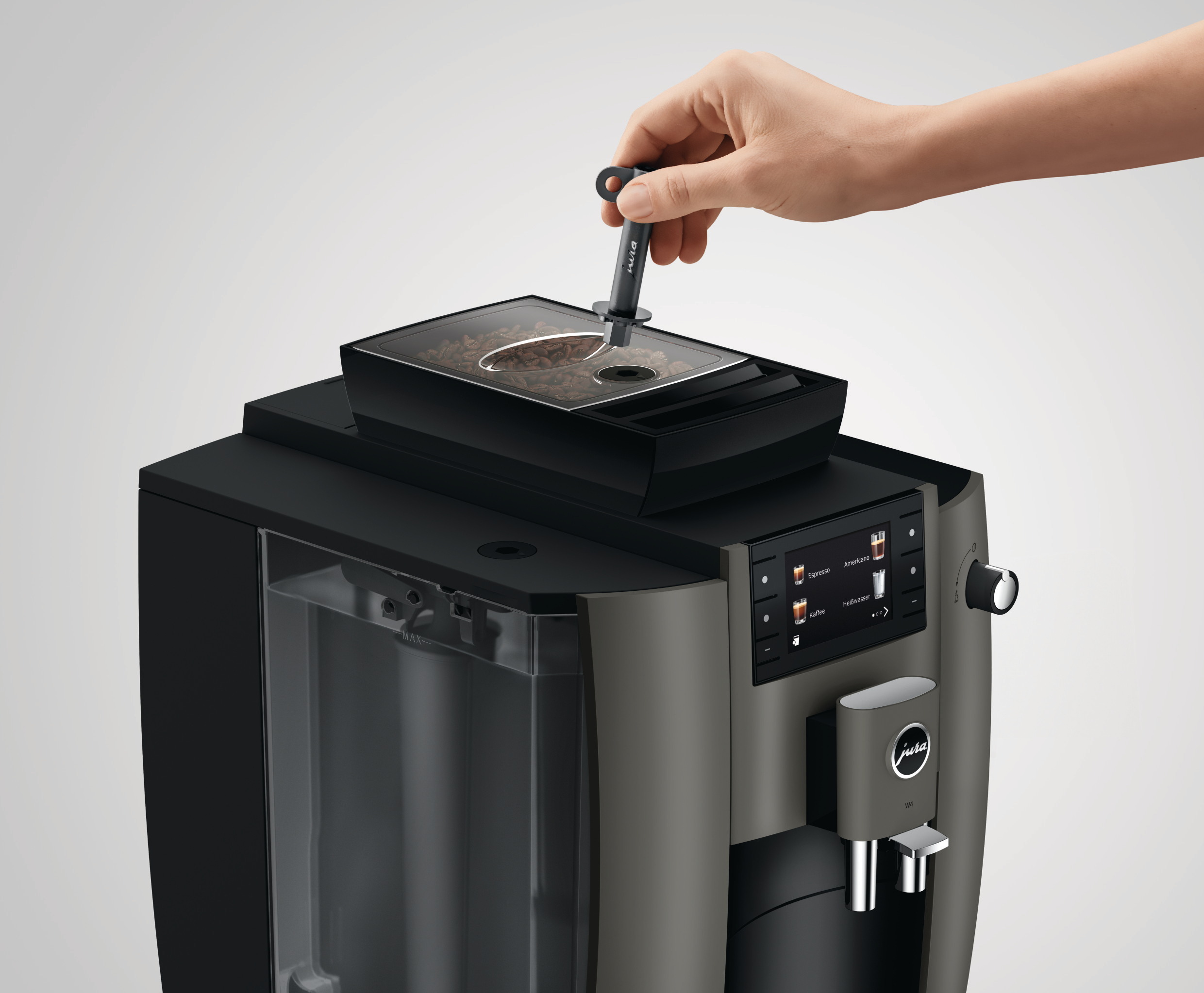 Eine Person fügt Kaffeebohnen in eine schwarze Kaffeemaschine ein.