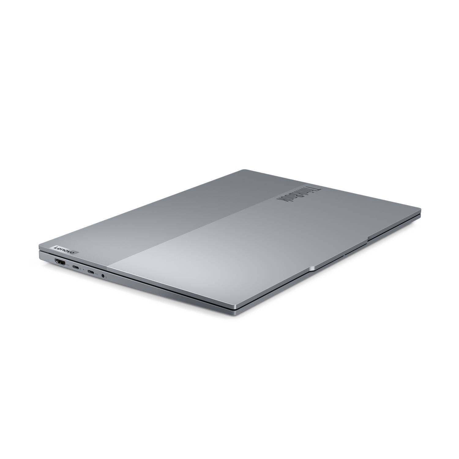A silver laptop on a white surface. The laptop is closed and angled towards the viewer.