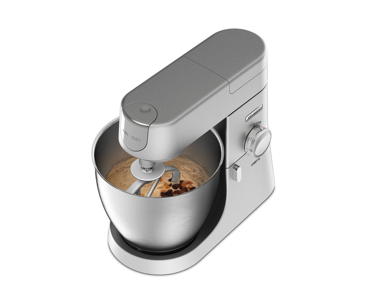 Srebrny mikser stojący Kenwood, miska wypełniona ciastem i rodzynkami. Z bliska, białe tło.