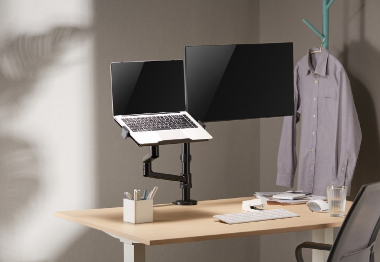 Laptop és monitor beállítása az asztalon. Fehér asztal, állvány és kiegészítők.