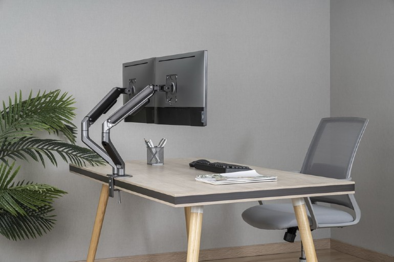 Számítógép-beállítás egy fa íróasztalon. Tartalmaz egy monitorkart és két monitort, egy székkel.