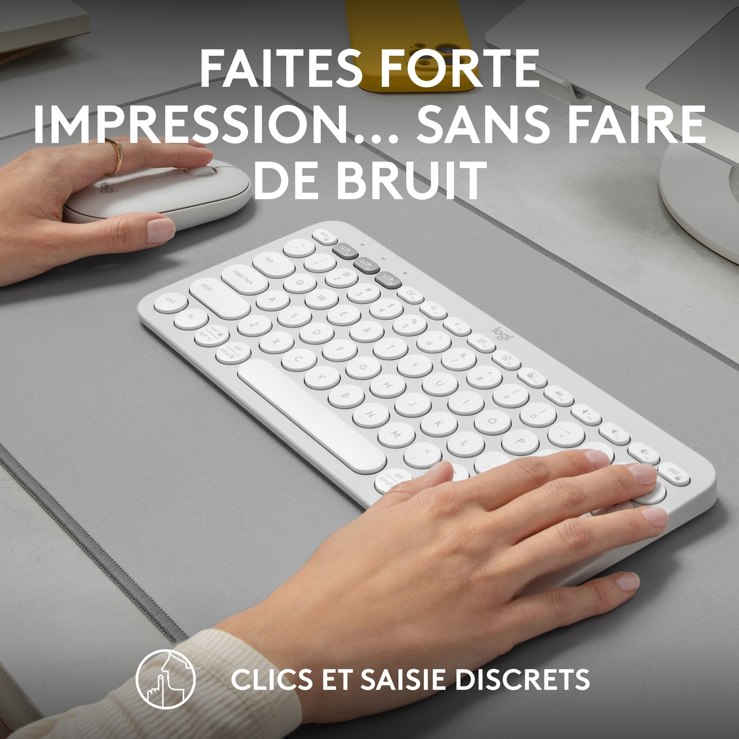 Les mains d'une personne sur un clavier blanc et une souris blanche sur un tapis gris. Le texte est en français.