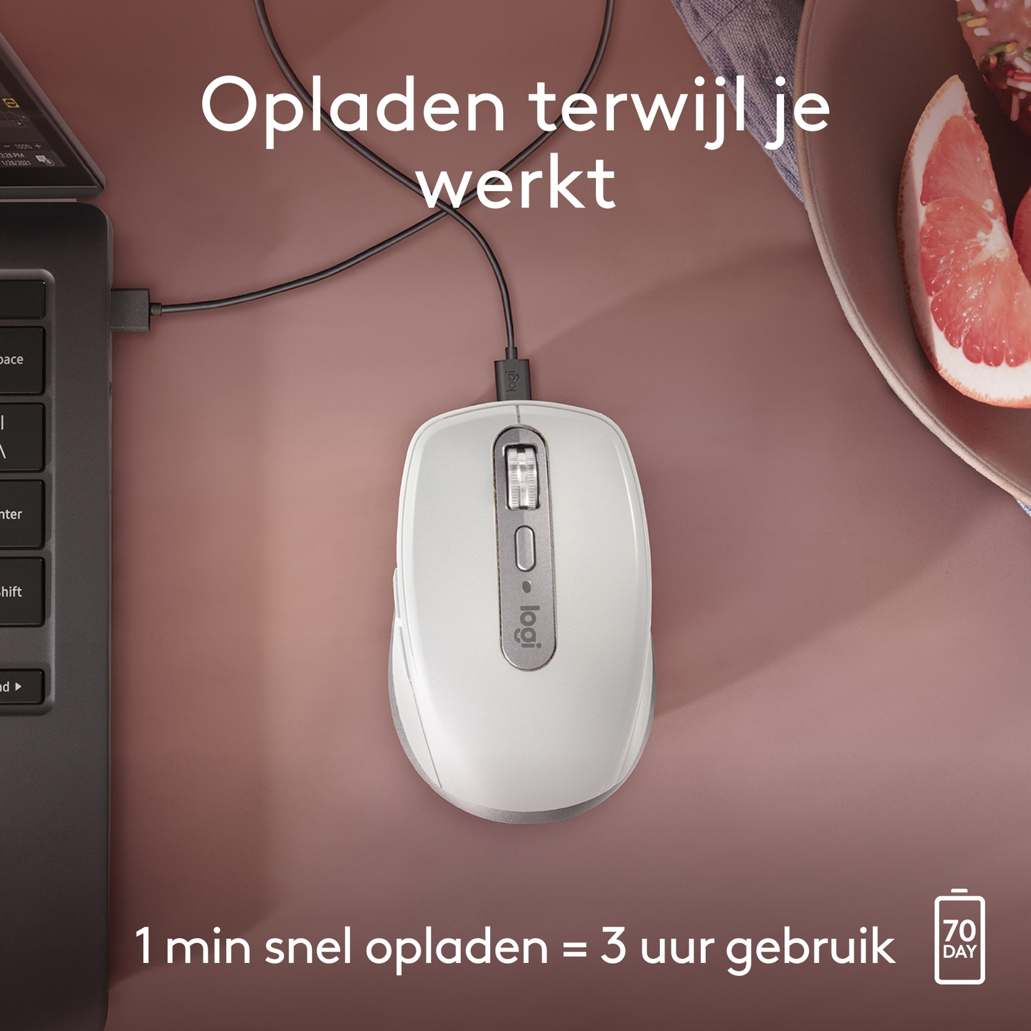 White mouse connected to a laptop charging on a brown table next to a plate with fruit.