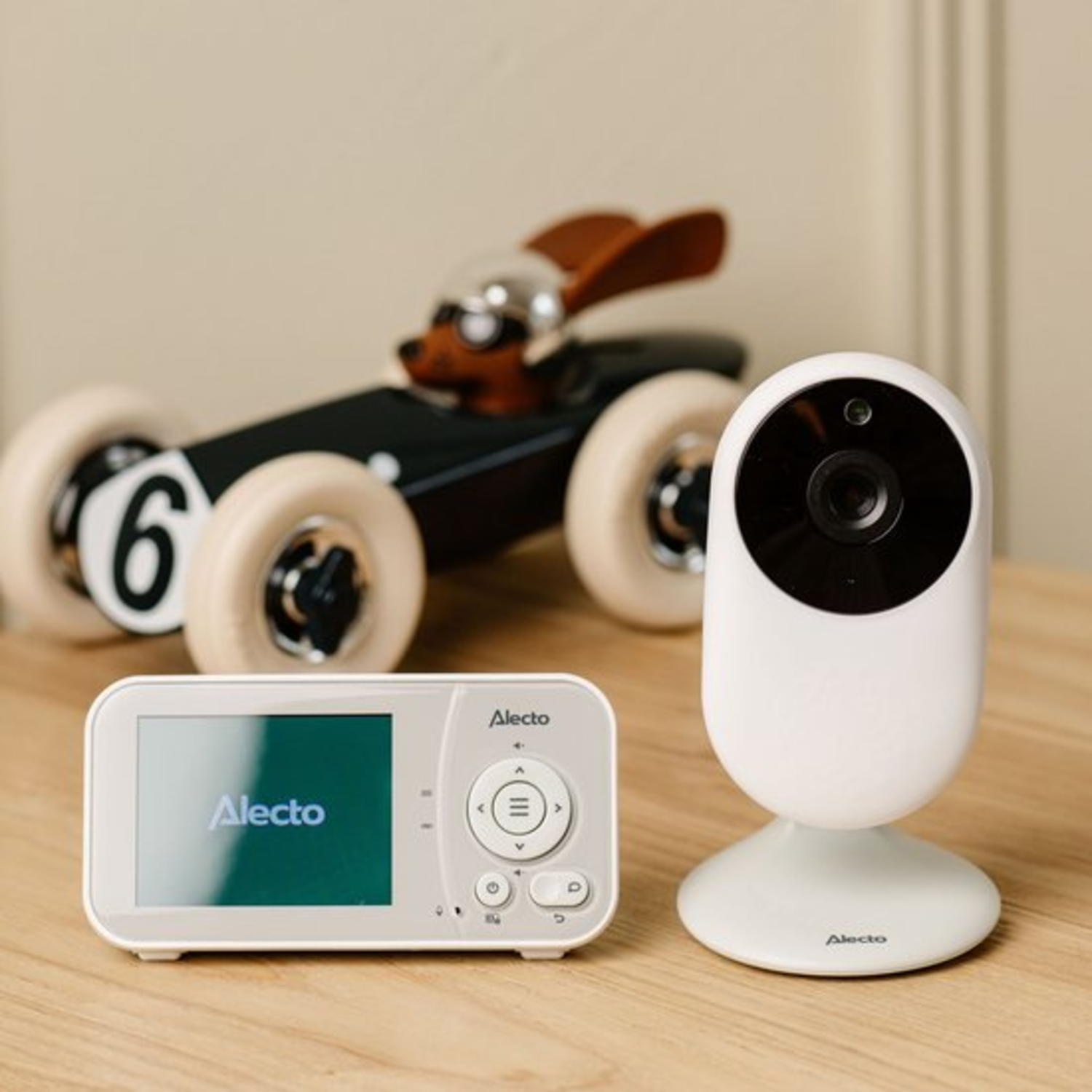 Baby monitor with camera and a wooden toy car. The monitor is white.