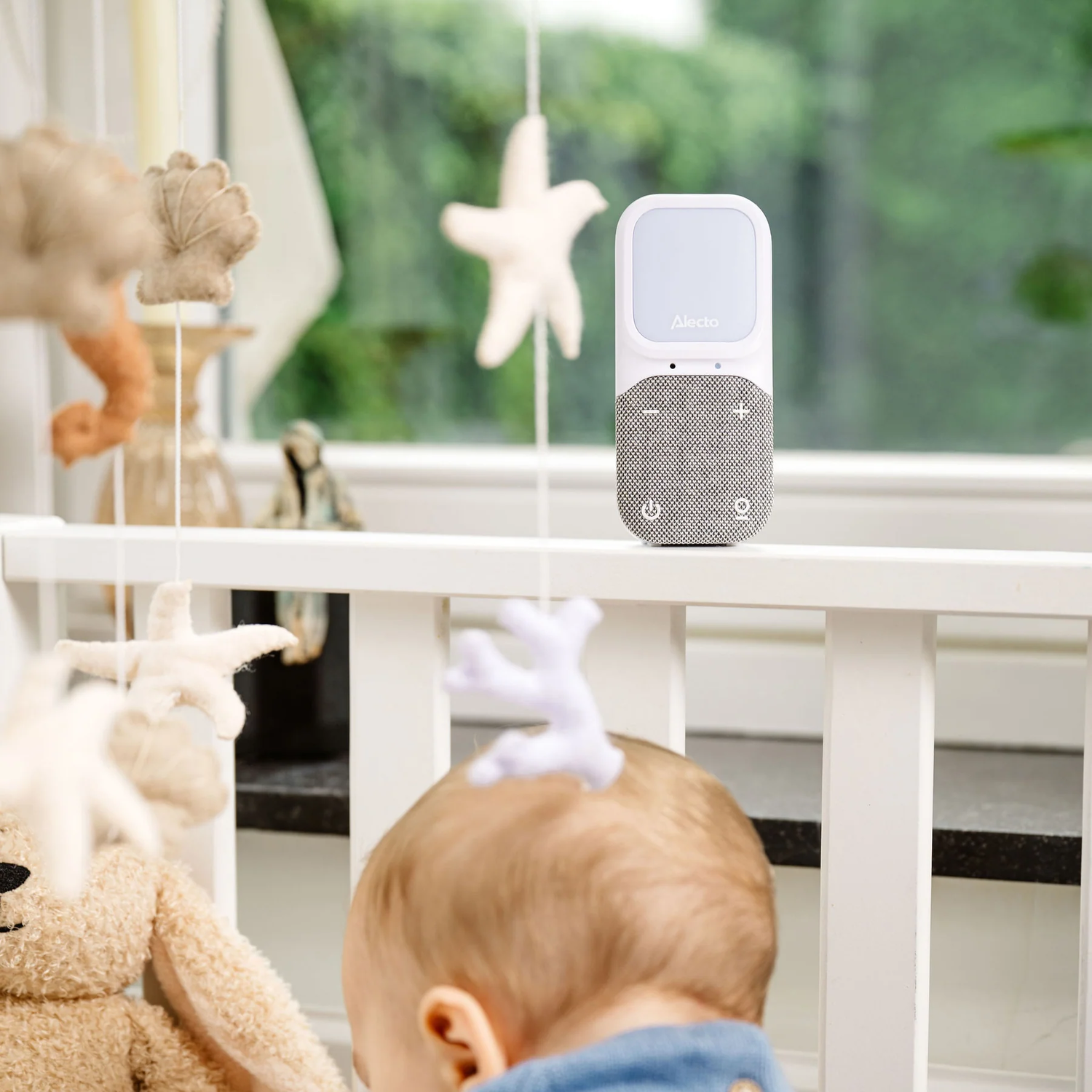Baby monitor on a white railing, with baby toys.