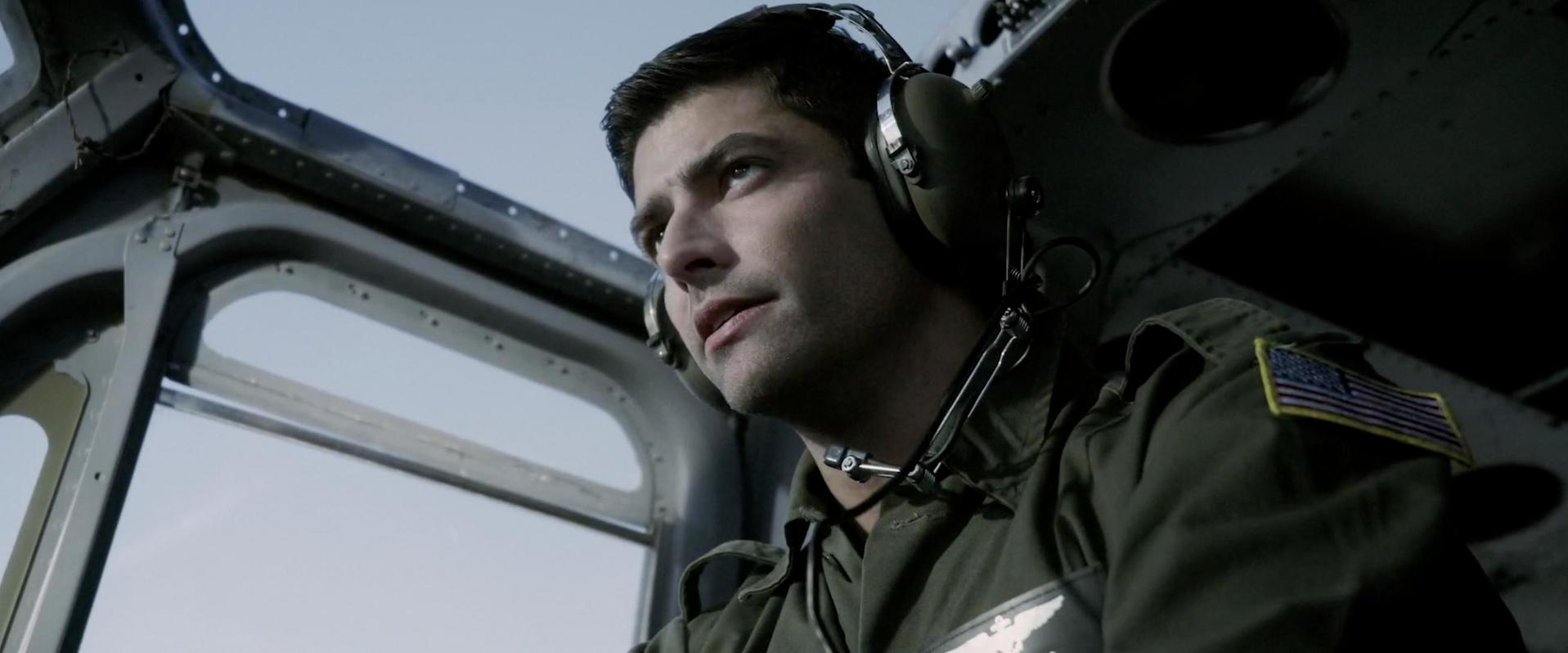 Ein Mann in Uniform mit Kopfhörern blickt nachdenklich aus einem Flugzeug.