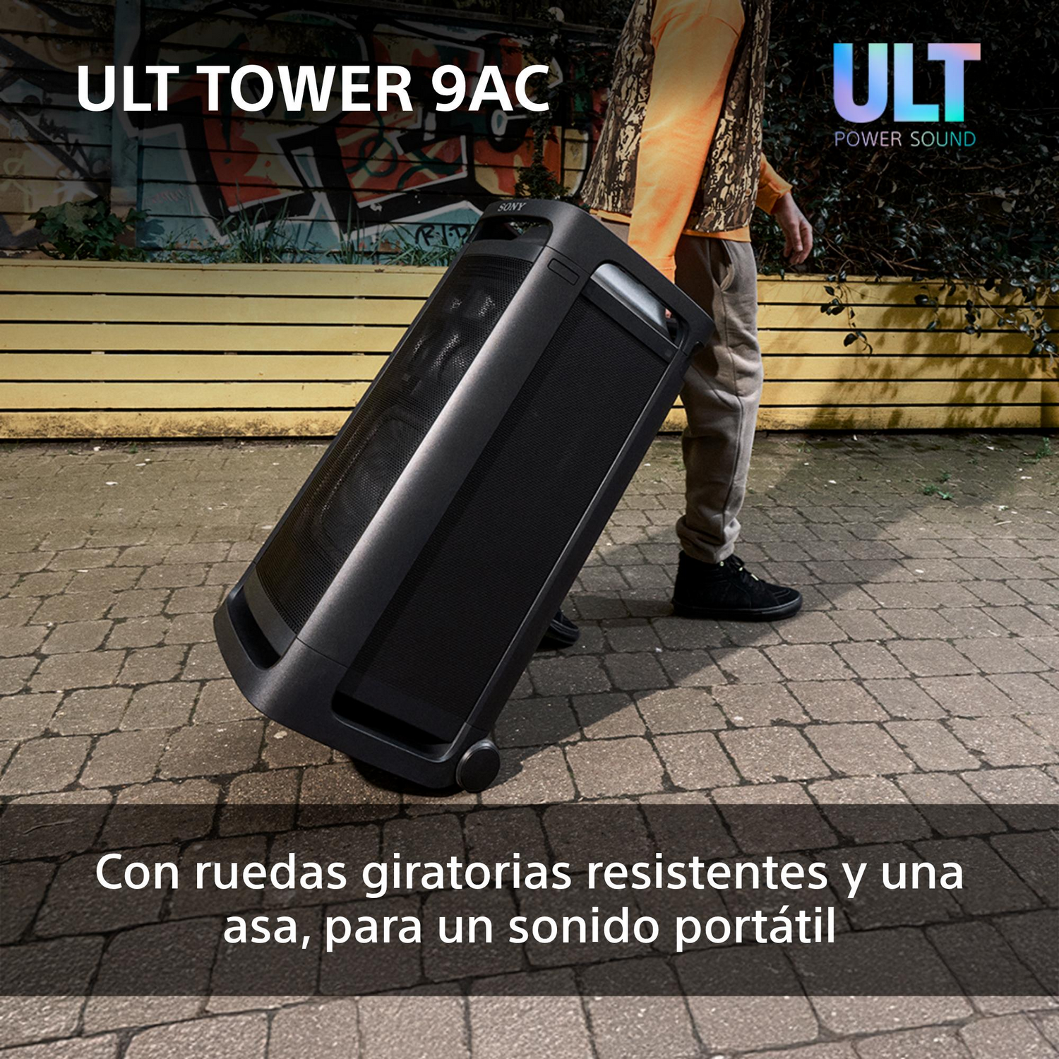 Una persona tirando de un altavoz negro sobre un carrito con ruedas.