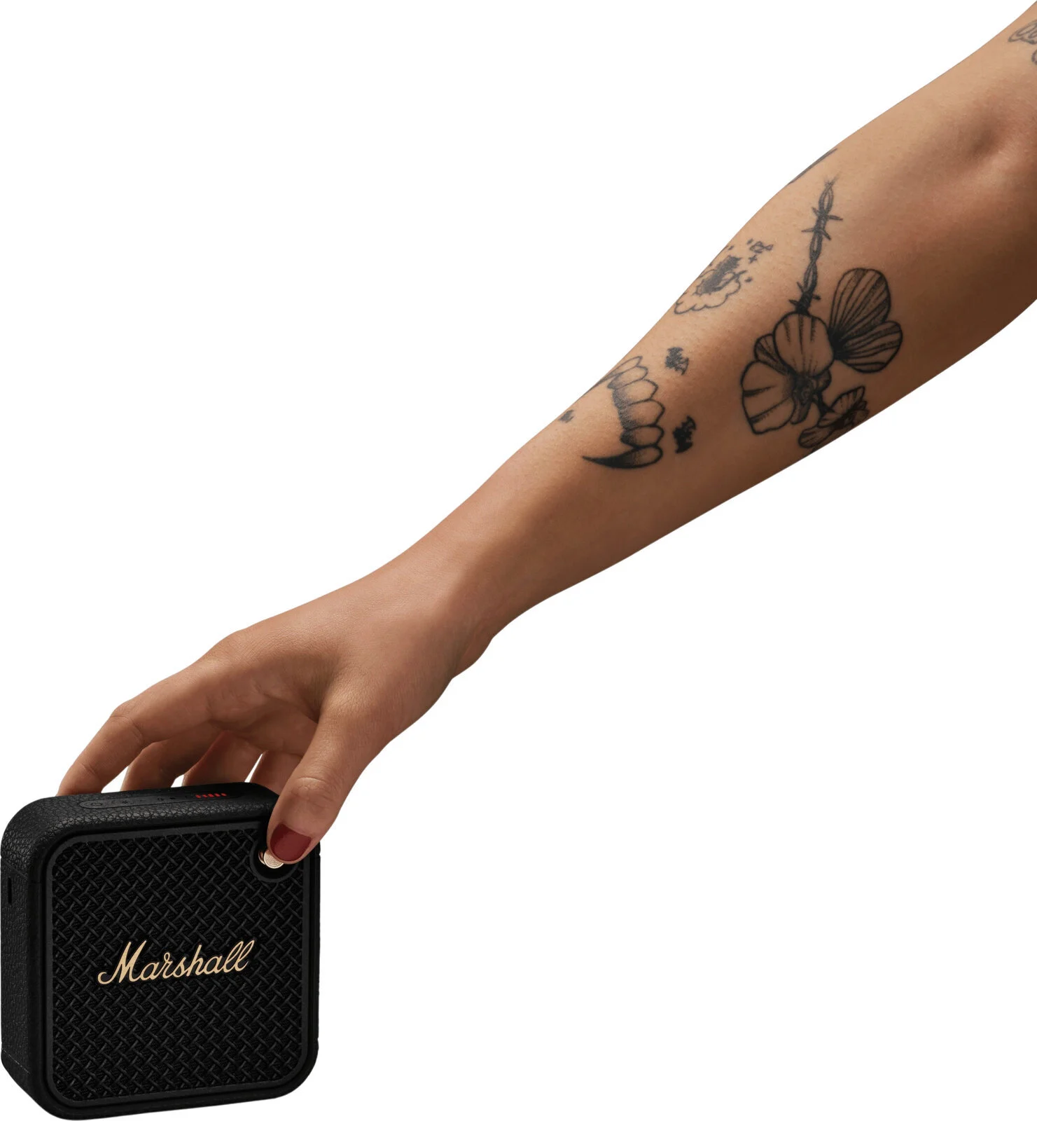 Una mano tiene un piccolo altoparlante Marshall nero. Il braccio ha tatuaggi.
