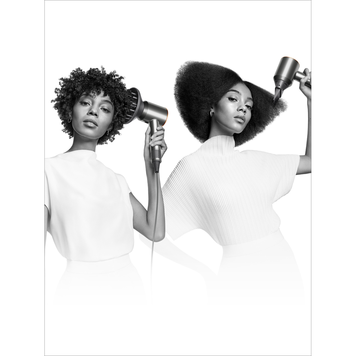 Two women with hair dryers. Both are wearing white. Black and white image.
