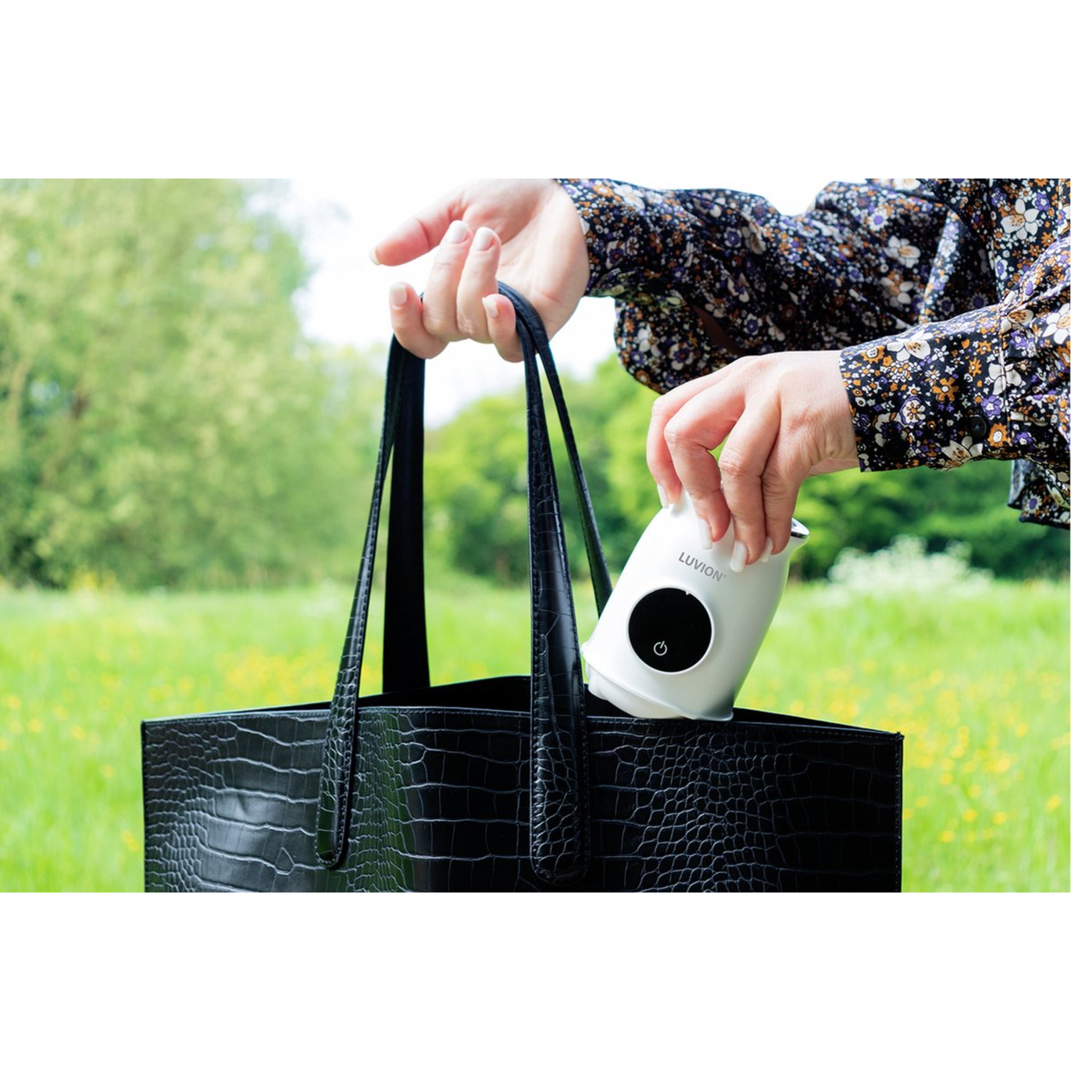 A woman putting a white device into a black bag.  Luvion is written on it.