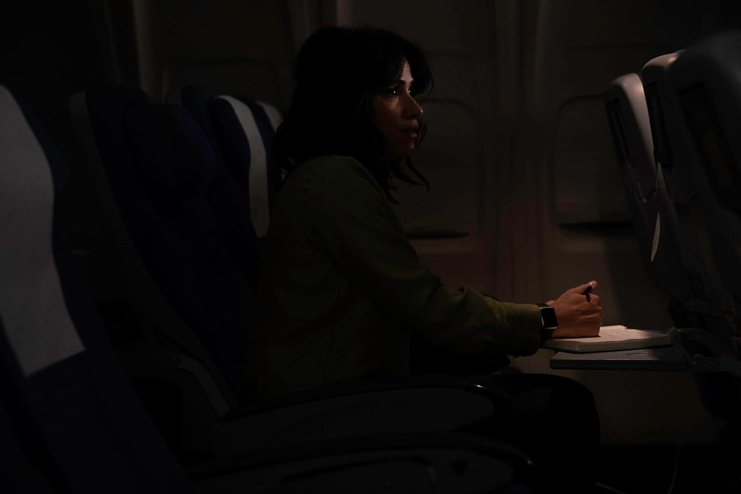 Frau im Flugzeug, blickt zum Fenster. Es ist dunkel. Der Sitz ist vorne.