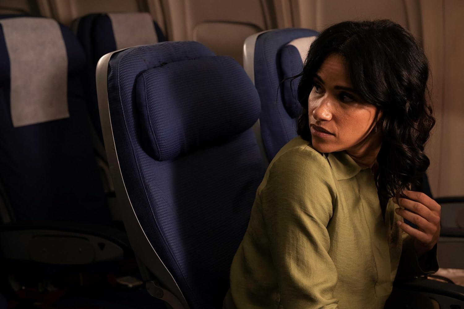 Eine Frau in einem Flugzeug blickt besorgt über ihre Schulter.