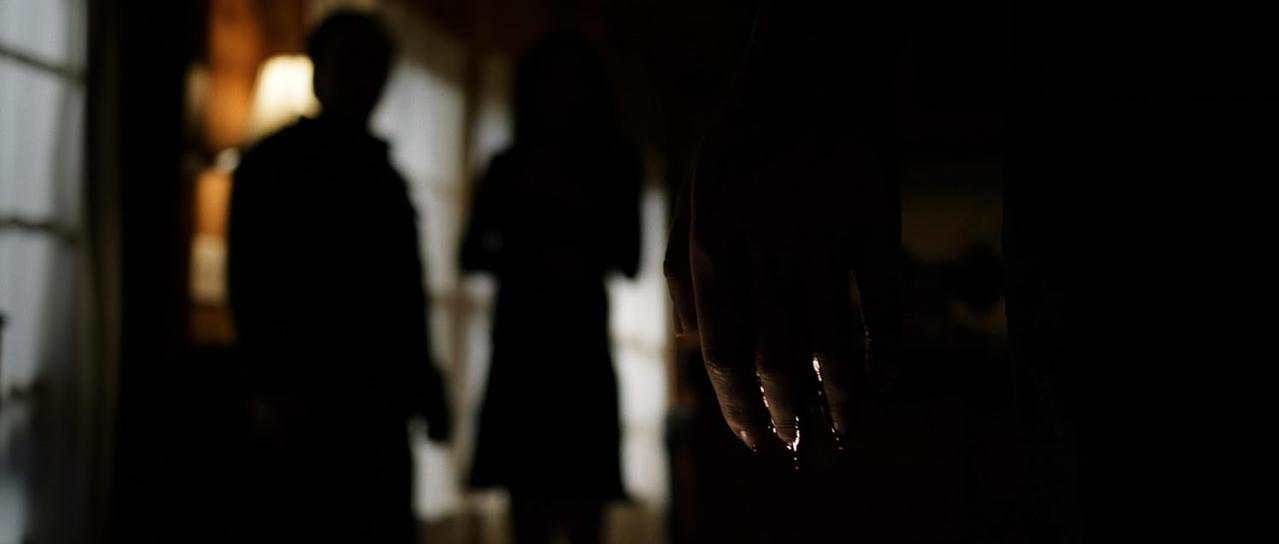 Dunkler Raum. Silhouetten von Personen, Hand greift aus. Schwaches Licht.