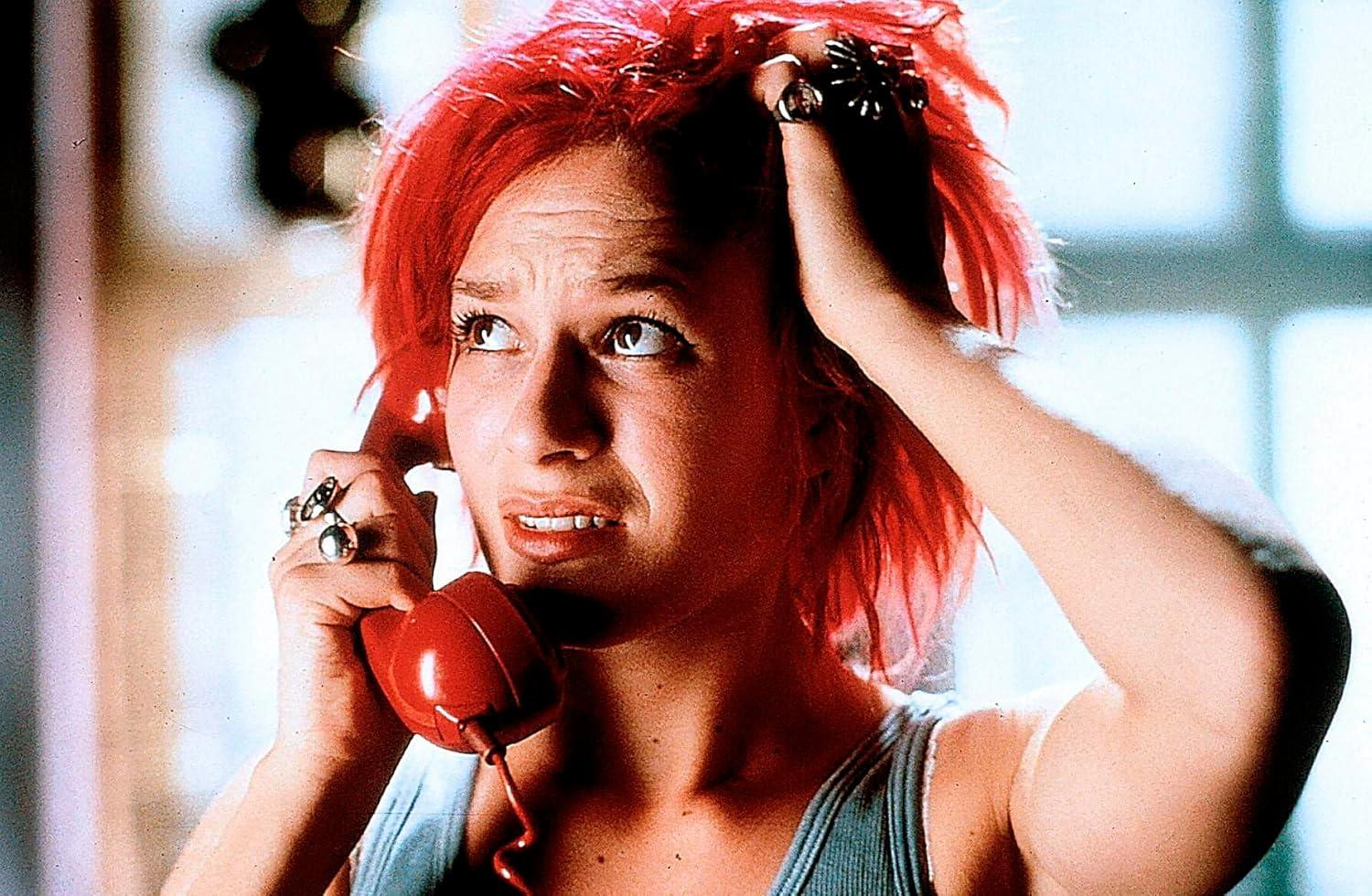Eine Frau mit roten Haaren sieht besorgt aus, während sie ein rotes Telefon an ihr Ohr hält.