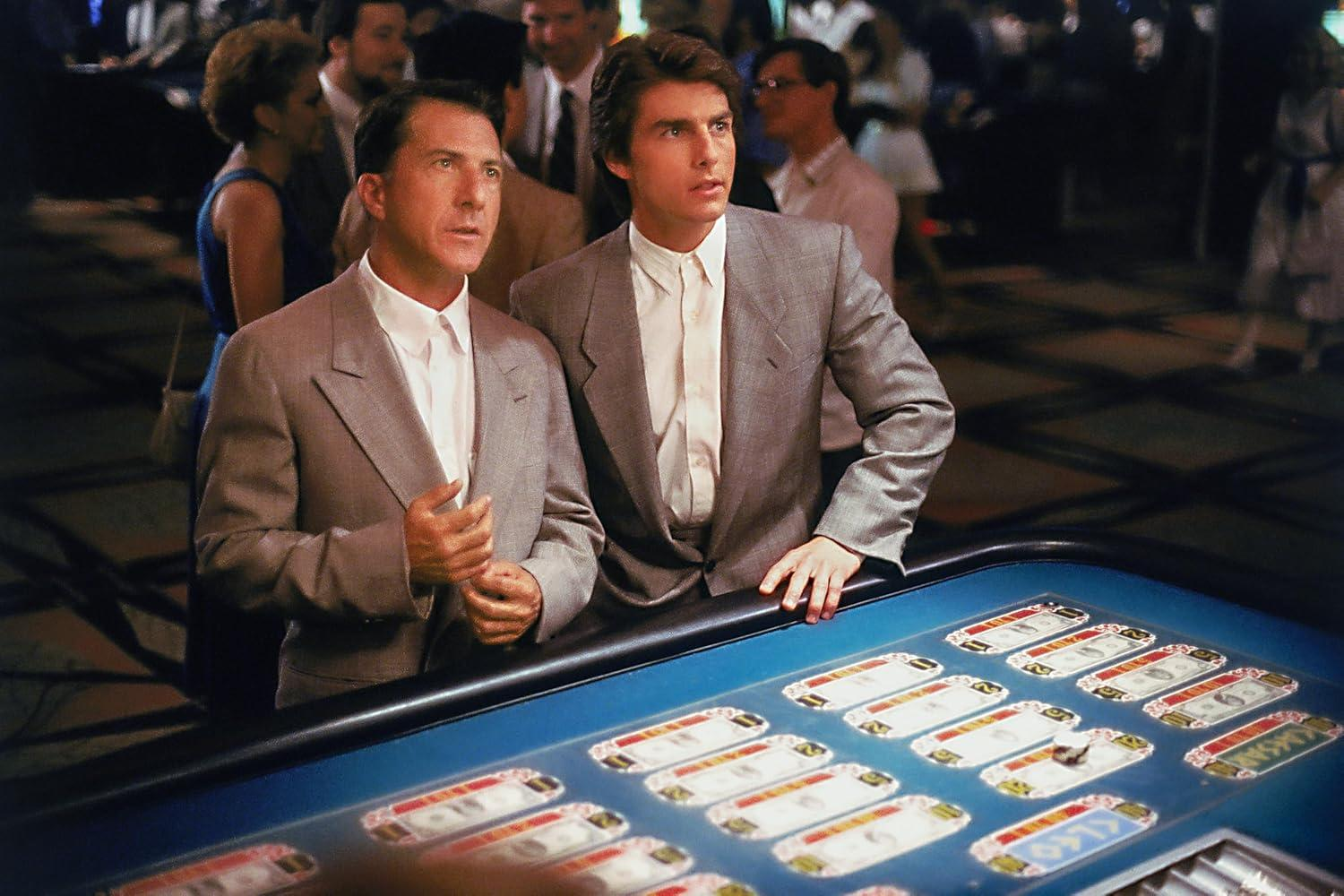 Zwei Männer in Anzügen an einem Casinotisch, einer blickt nach oben, der andere nach vorne.