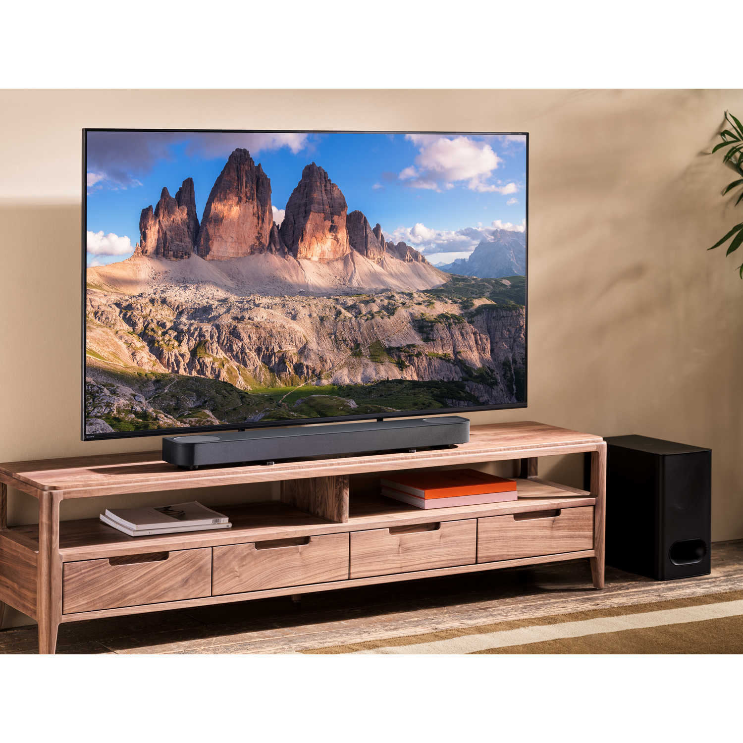 Een tv-scherm met een landschap, met een soundbar en subwoofer eronder.