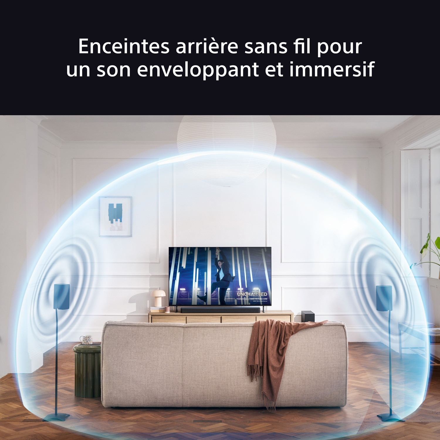 Salon avec TV, barre de son, deux enceintes, canapé et couverture. Une onde sonore bleue.