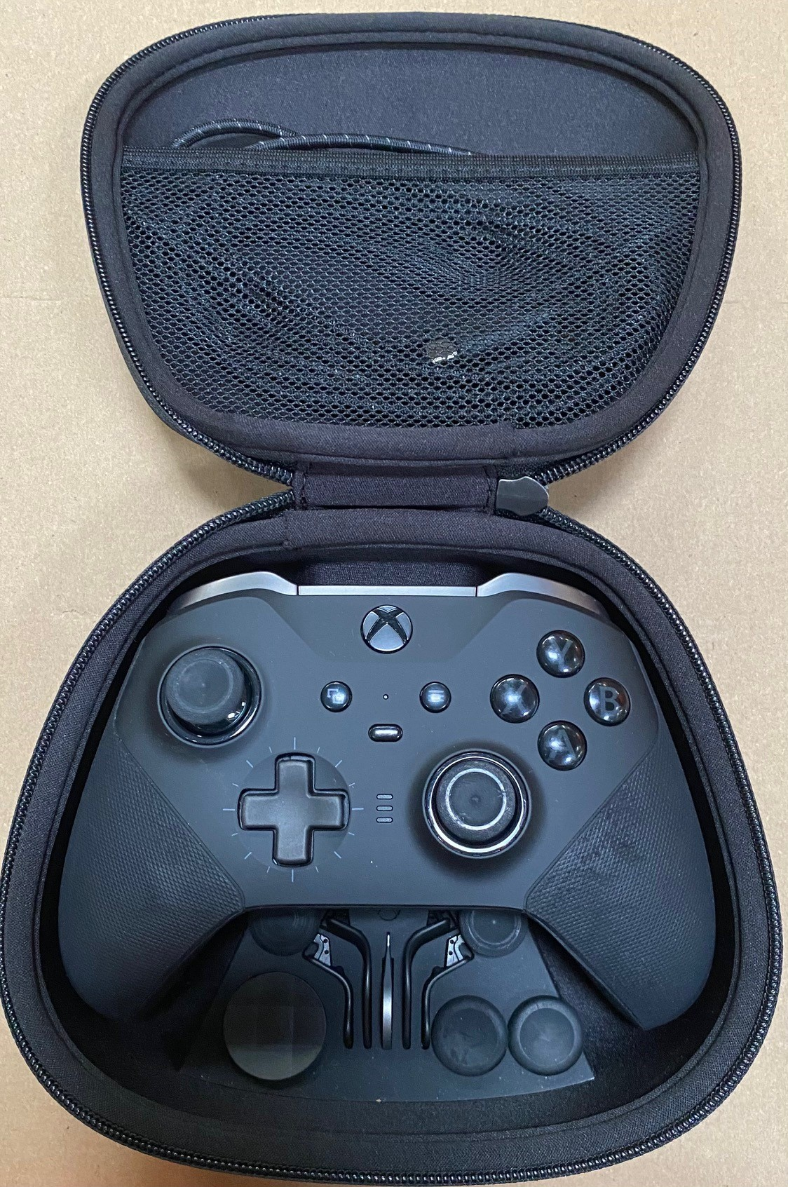 Otwarta, czarna obudowa kontrolera Xbox ujawniająca kontroler. Obudowa jest czarna.
