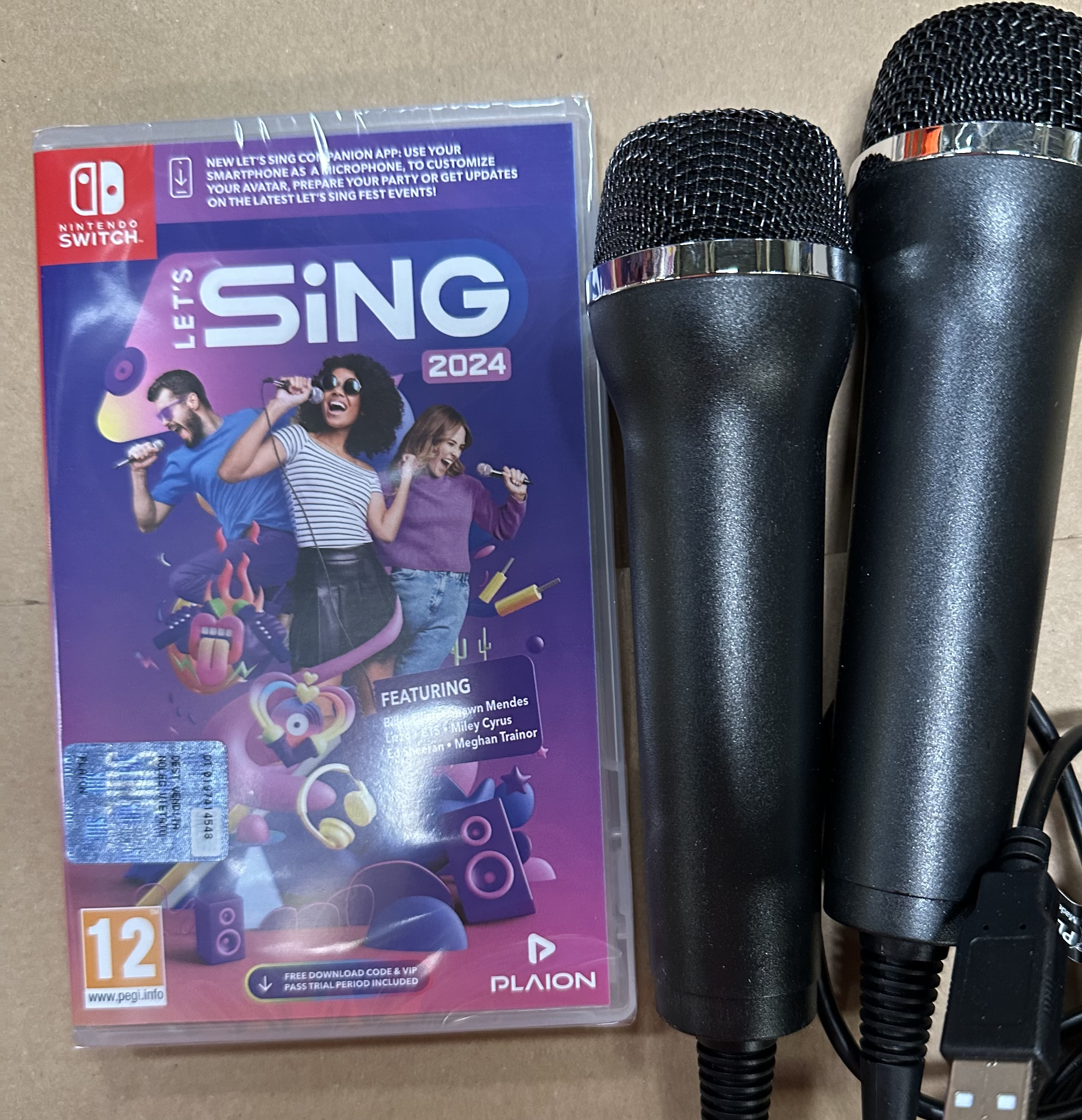 Etui na grę Nintendo Switch i czarne mikrofony, na jasnobrązowej powierzchni.