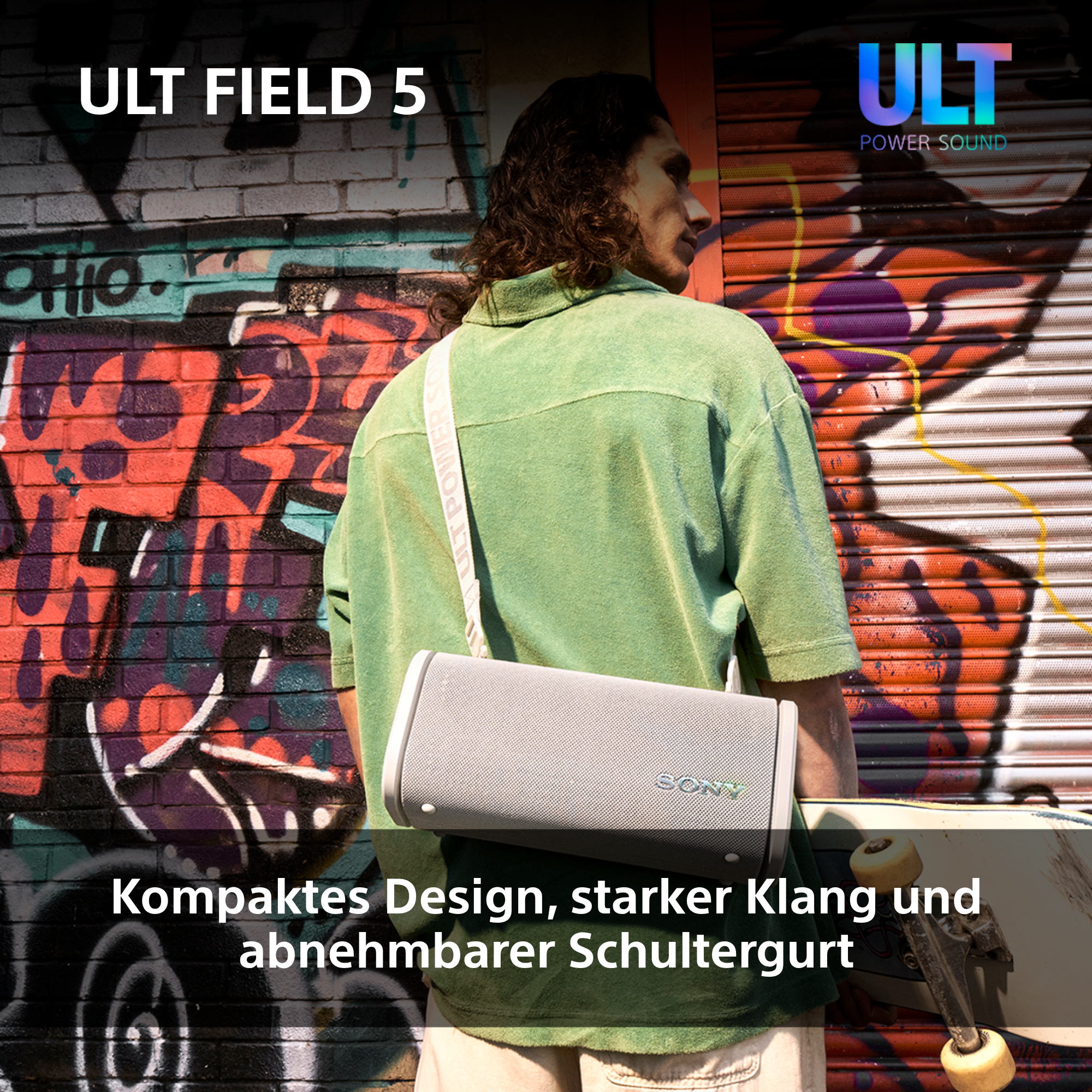 Ein Mann steht mit einem grauen Lautsprecher, der Hintergrund ist eine Graffiti-Wand. ULT Power Sound Logo.