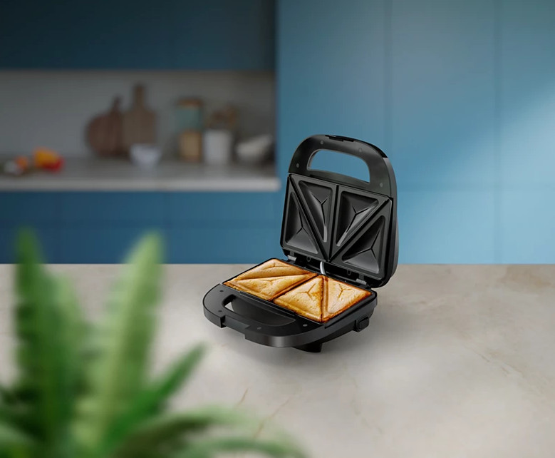 Czarny opiekacz do kanapek otwarty, z ugotowanymi kanapkami w środku, na białej powierzchni.