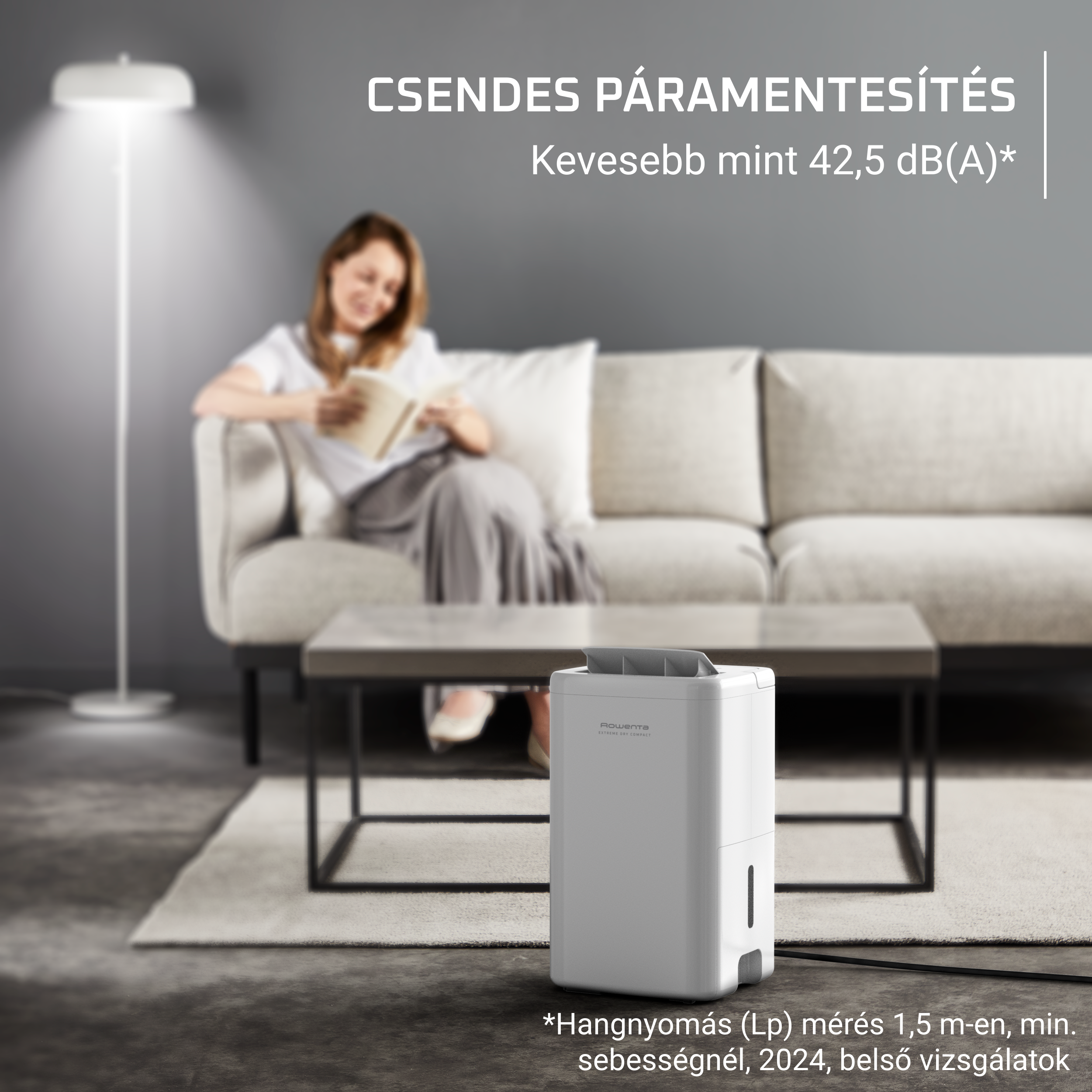 Egy nő könyvet olvas a kanapén, fehér párátlanítóval a padlón.