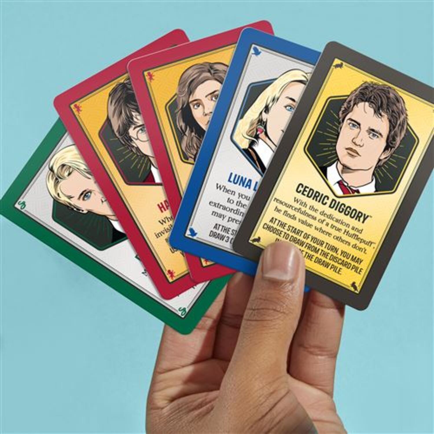 Hand holding four Harry Potter character cards, close up.