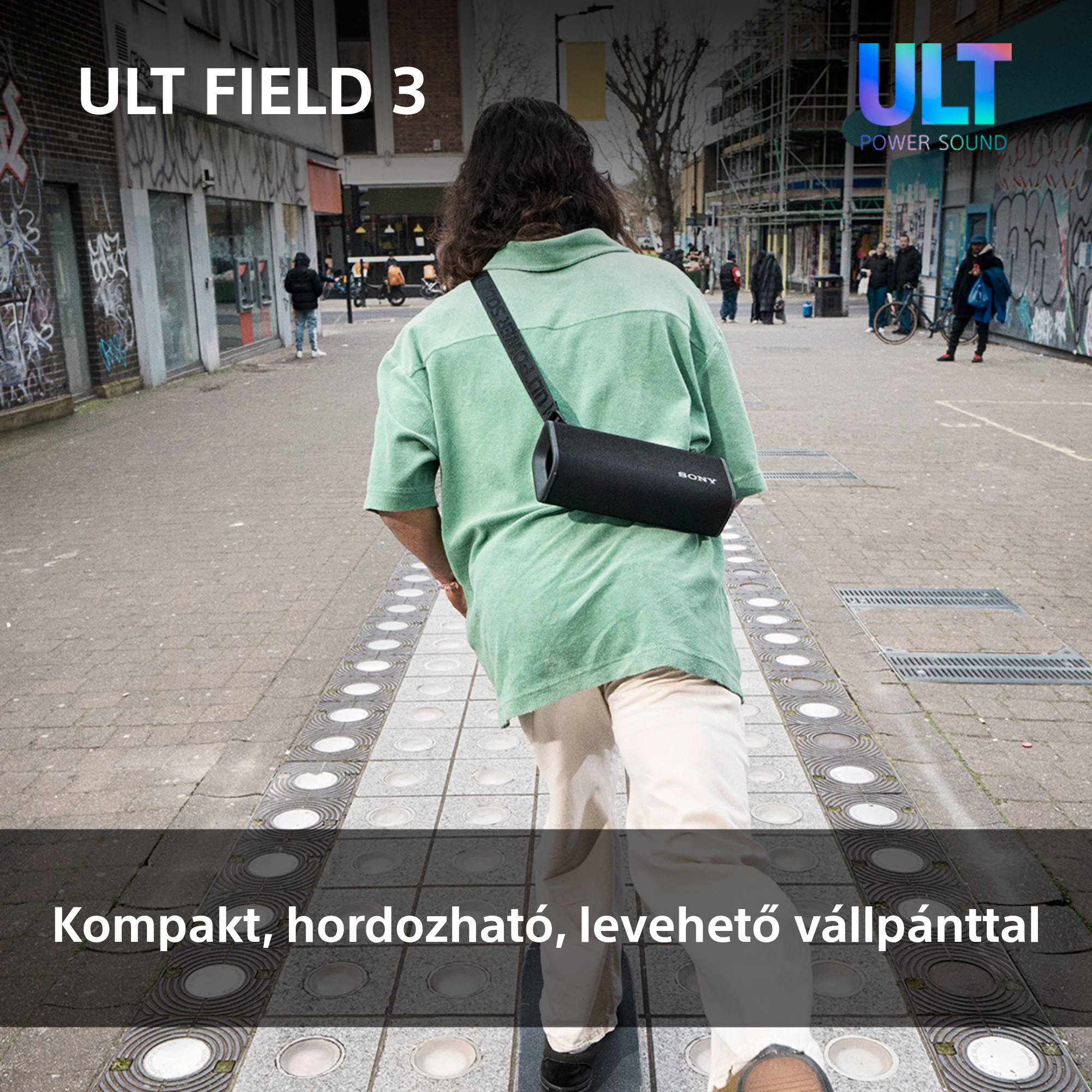 Férfi sétál, egy fekete, hengeres hangszórót tartva, vállpánttal.