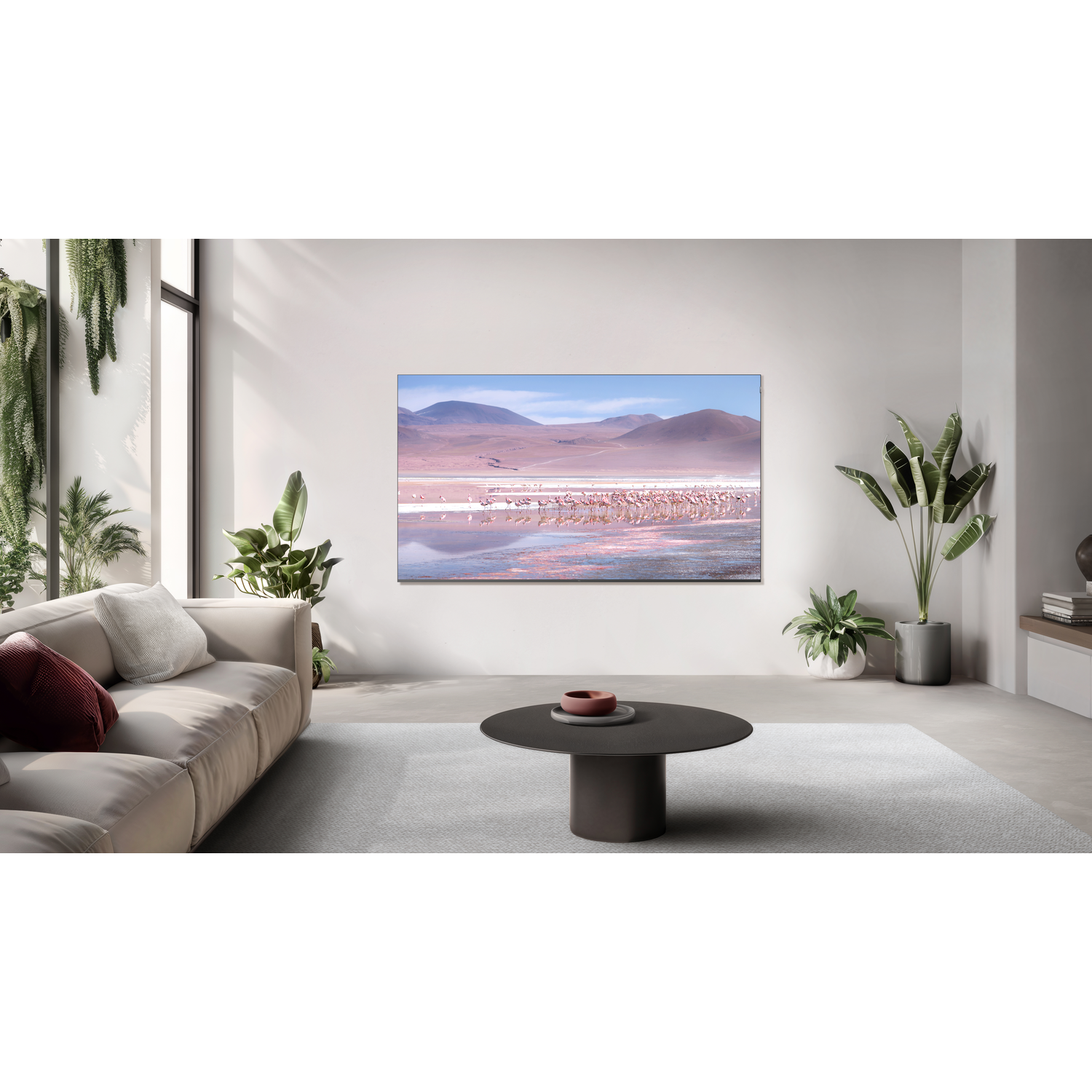 Kamer met tv die een landschap toont. Bank, ronde tafel, planten en een raam.