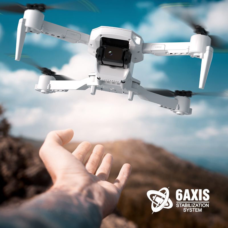 Beyaz drone uçuyor, alttan görünüm, arka planda dağ.